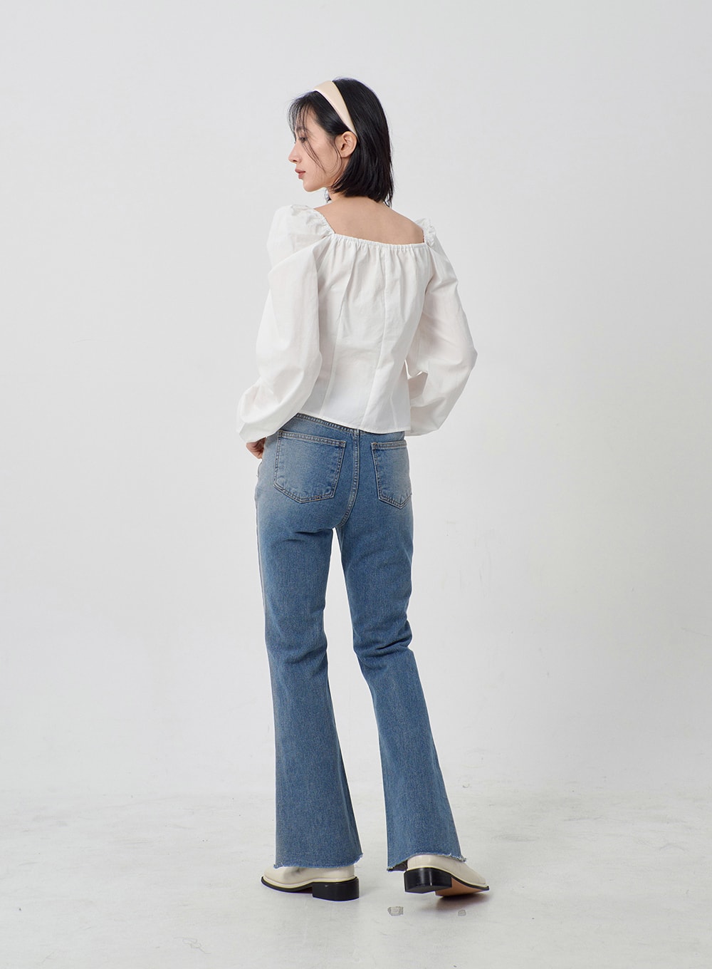 Light Washed Bootcut Jeans OD27 in light blue, back full-length view on model, rear five-pocket detail, slim-fit washed denim, subtle bootcut flare from knee with raw frayed hem, paired with white blouse.