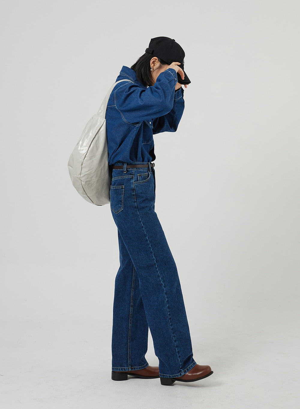 Basic Indigo Jeans OF310 in indigo, full-length side profile on model mid-motion, wide straight leg from high waist to ankle, styled with denim shirt, leather belt, and gray shoulder bag.