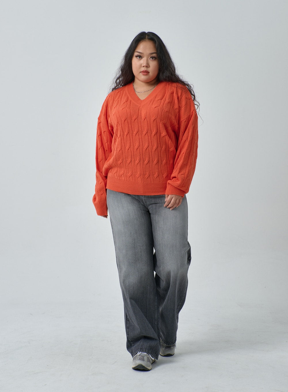 Plus Light Wash Wide Leg Jeans IF317 in grey wash, full-body walking shot on plus-size model, relaxed wide leg silhouette in faded denim, paired with orange cable-knit sweater and sneakers.