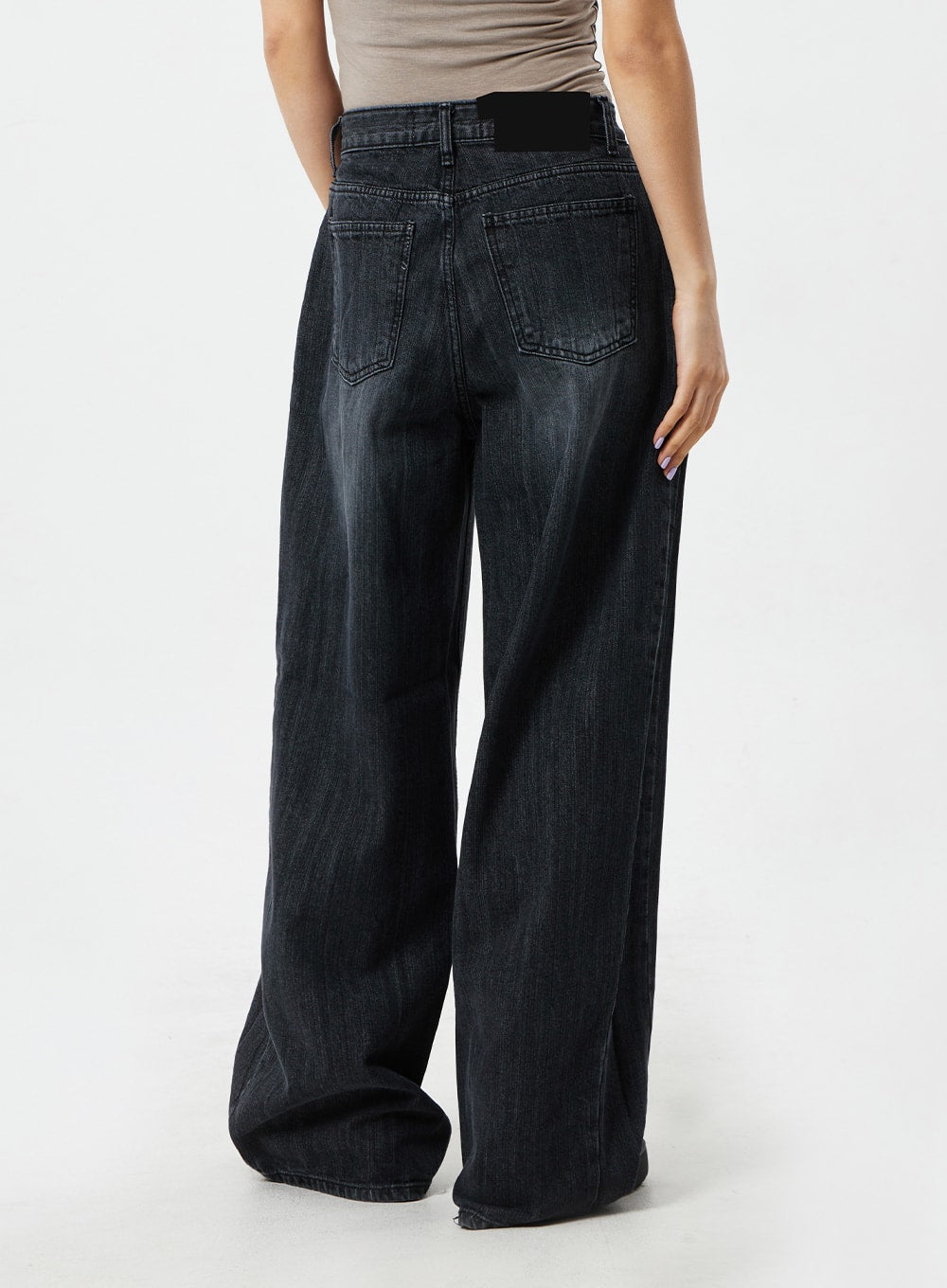 Mid-Rise Baggy Jeans CM324 in washed black denim, back view waist-to-hem close-up on model, dual back pockets with brand patch, wide-leg hem grazing the floor.