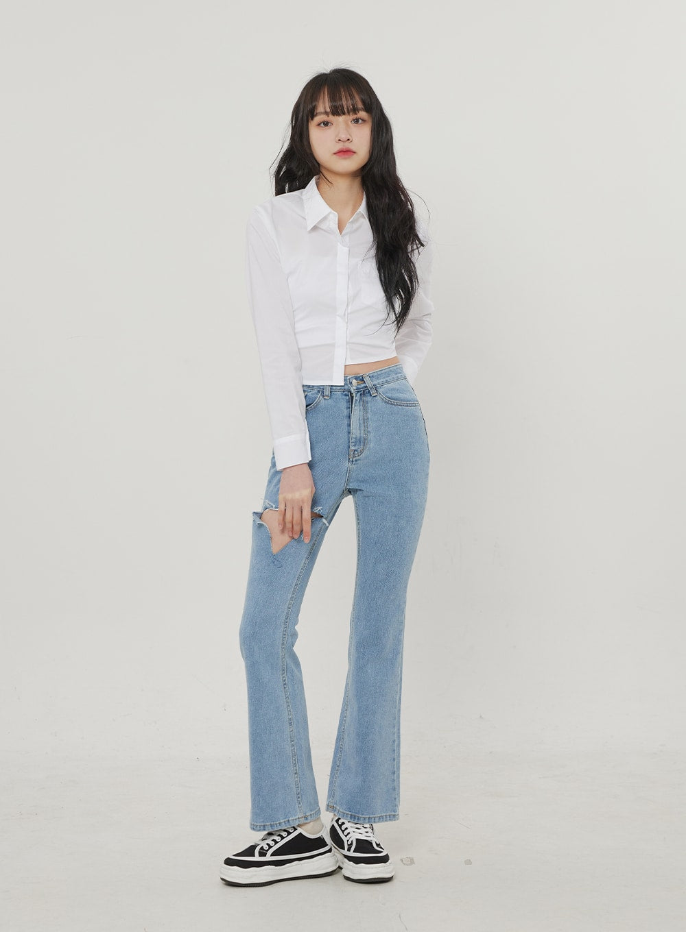 LEWKIN Ripped Bootcut Jeans BF306 in light blue, front full-body on model, slim-fit high-rise denim with large thigh rip, paired with white crop shirt and black sneakers.