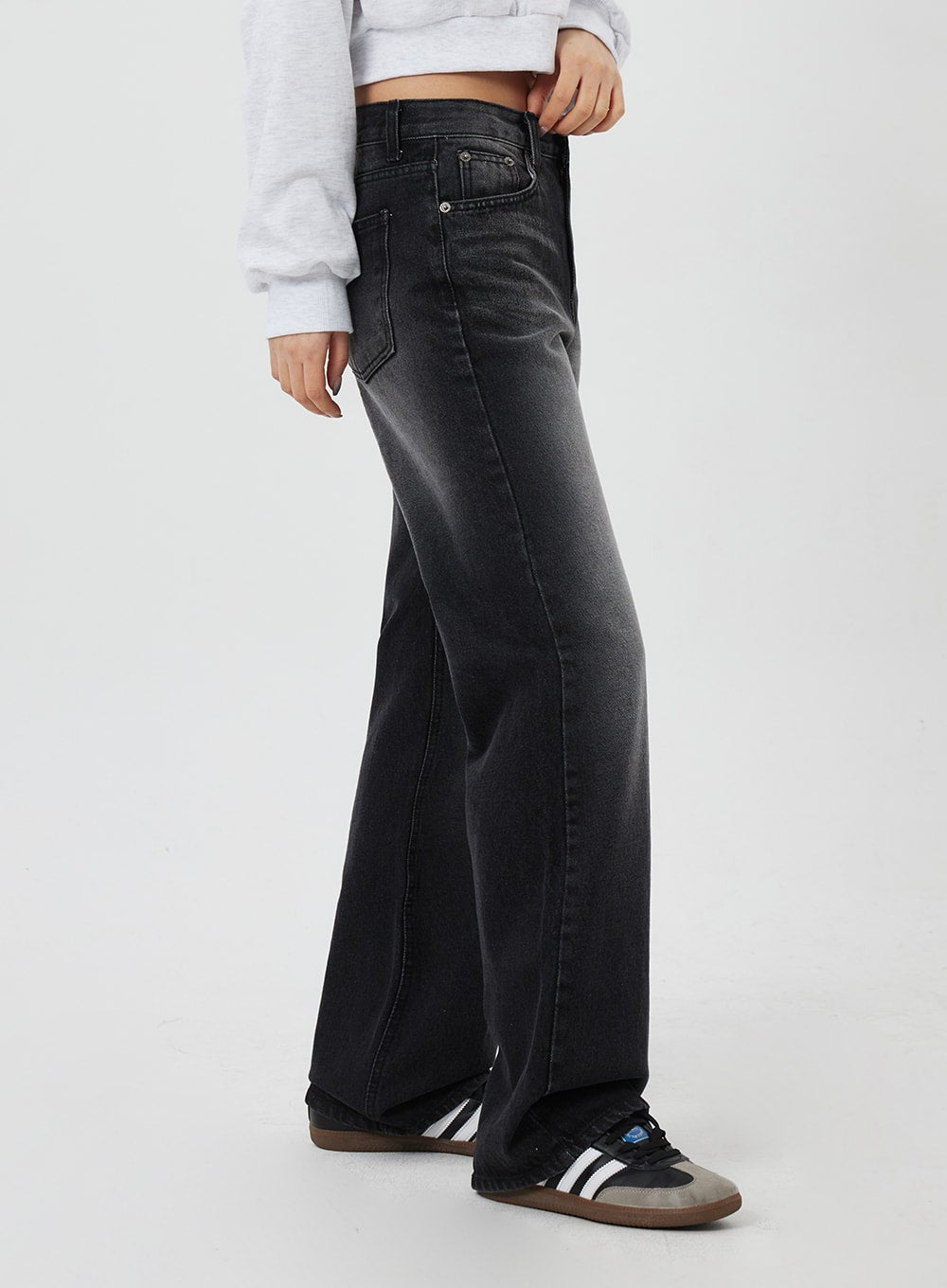 Mid-Rise Bootcut Jeans CF327 in black, side view close-up on model, bootcut flare from knee visible, faded washed cotton denim with side seam detail, styled with sneakers.
