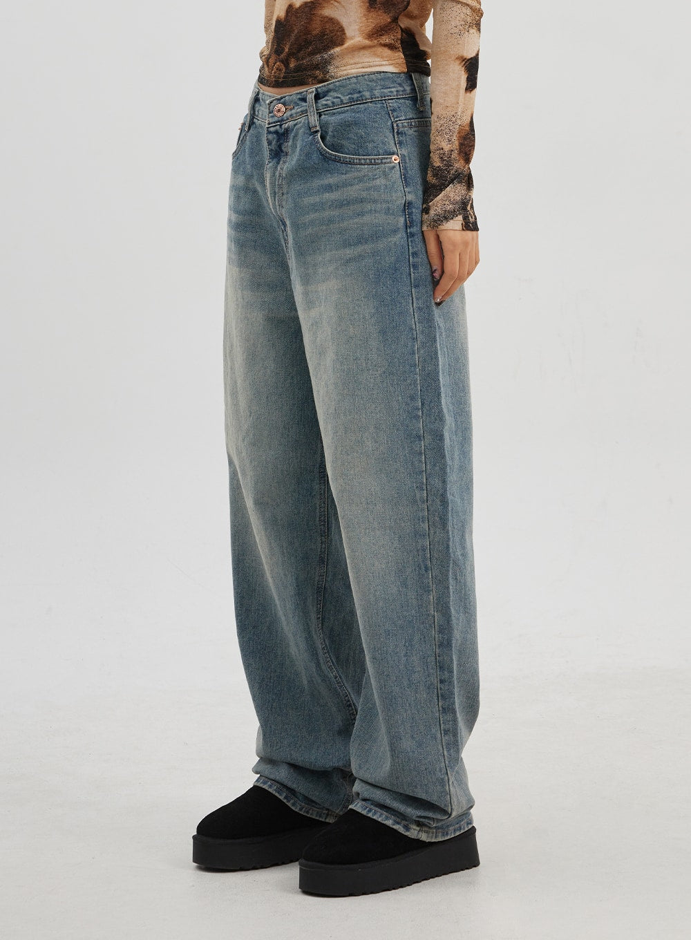 Low Rise Baggy Jeans CJ330 in Blue, side-angle waist-to-hem shot on model, wide-leg silhouette with whiskering and sun-faded wash, low-rise waistband with rose-gold button.