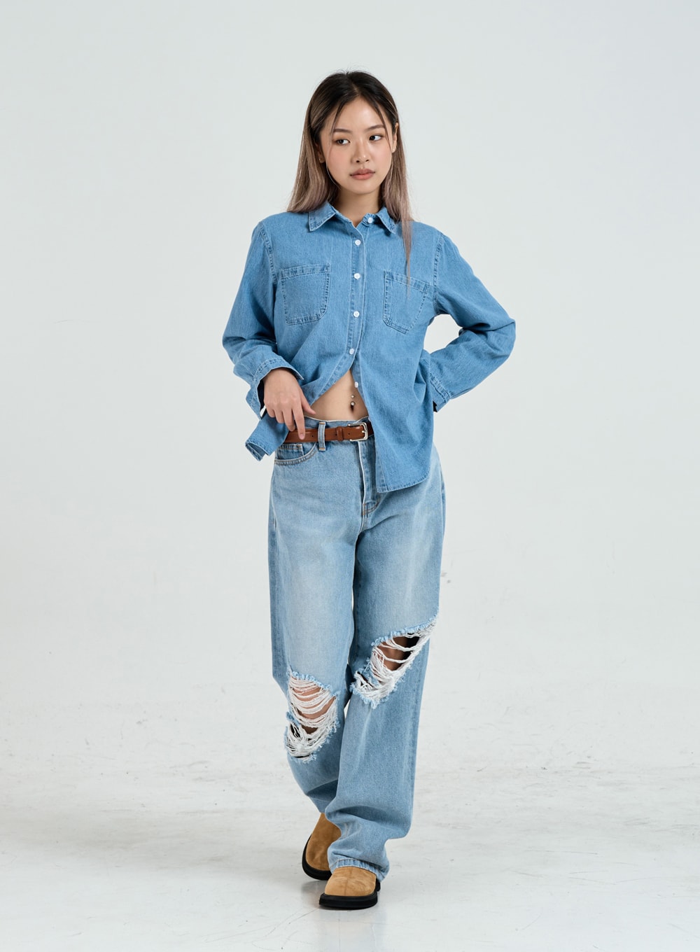 Ripped Maxi Denim Pants Unisex CO14 in light blue, full-body front walking pose on model, wide-leg destroyed denim with frayed knee rips, styled with denim shirt and brown belt.