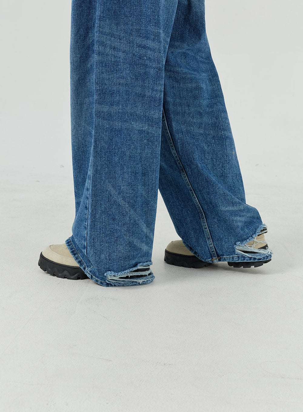 Oversized Jeans Unisex CM321 in blue, hem close-up detail, wide-leg denim with raw frayed hem edge pooling over chunky sneakers.