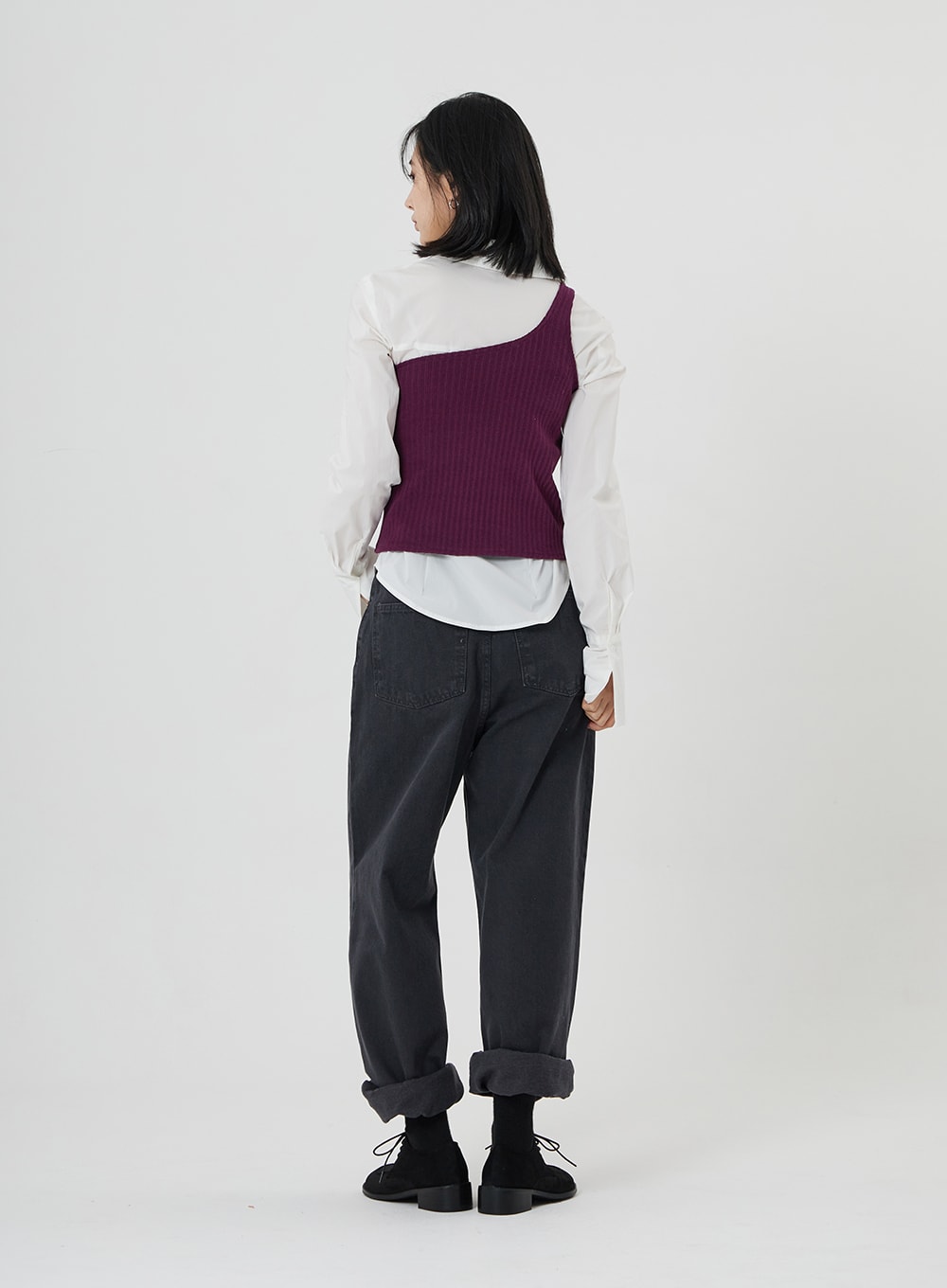 Maxi Denim Pants ON23 in charcoal grey, full-body back view on model, wide-leg cotton denim with cuffed hem and back pockets, styled with white shirt and purple asymmetric vest.