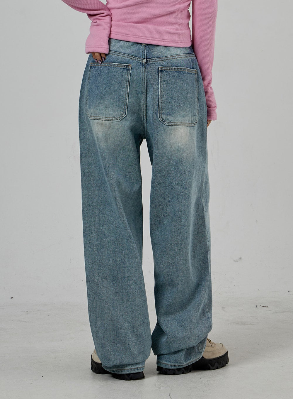 Light Wash Baggy Jeans Unisex CD26 in light blue, back view waist-to-hem close-up, large patch back pockets with washed fading, wide baggy leg in cotton denim, chunky sole shoes.