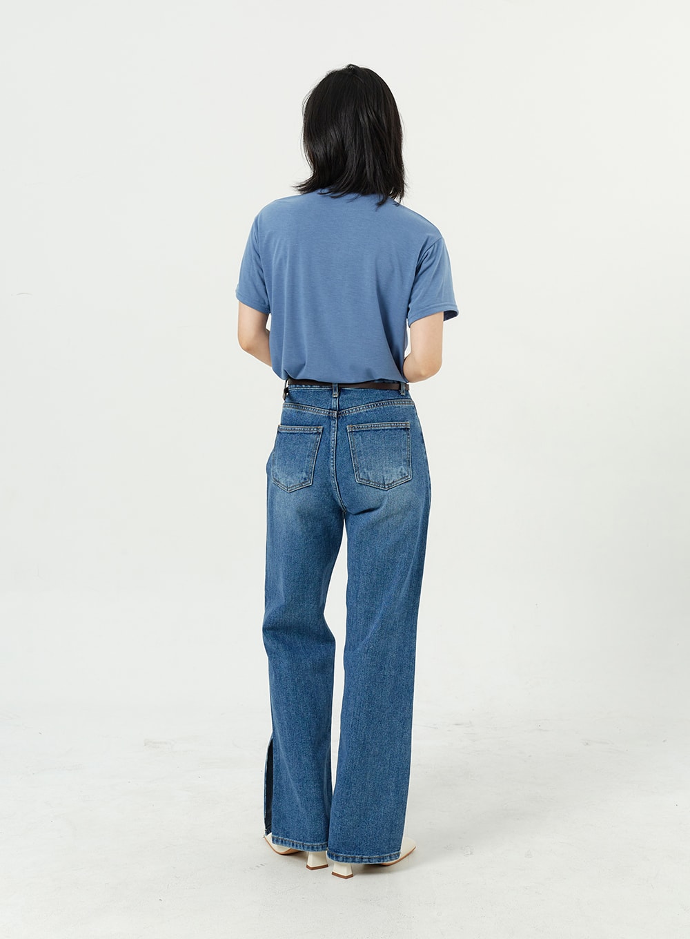 Side Slit Jeans OM308 in mid blue, full-length back shot on model, wide-leg cotton denim with back pockets and hem side slits visible, paired with blue tee and white boots.