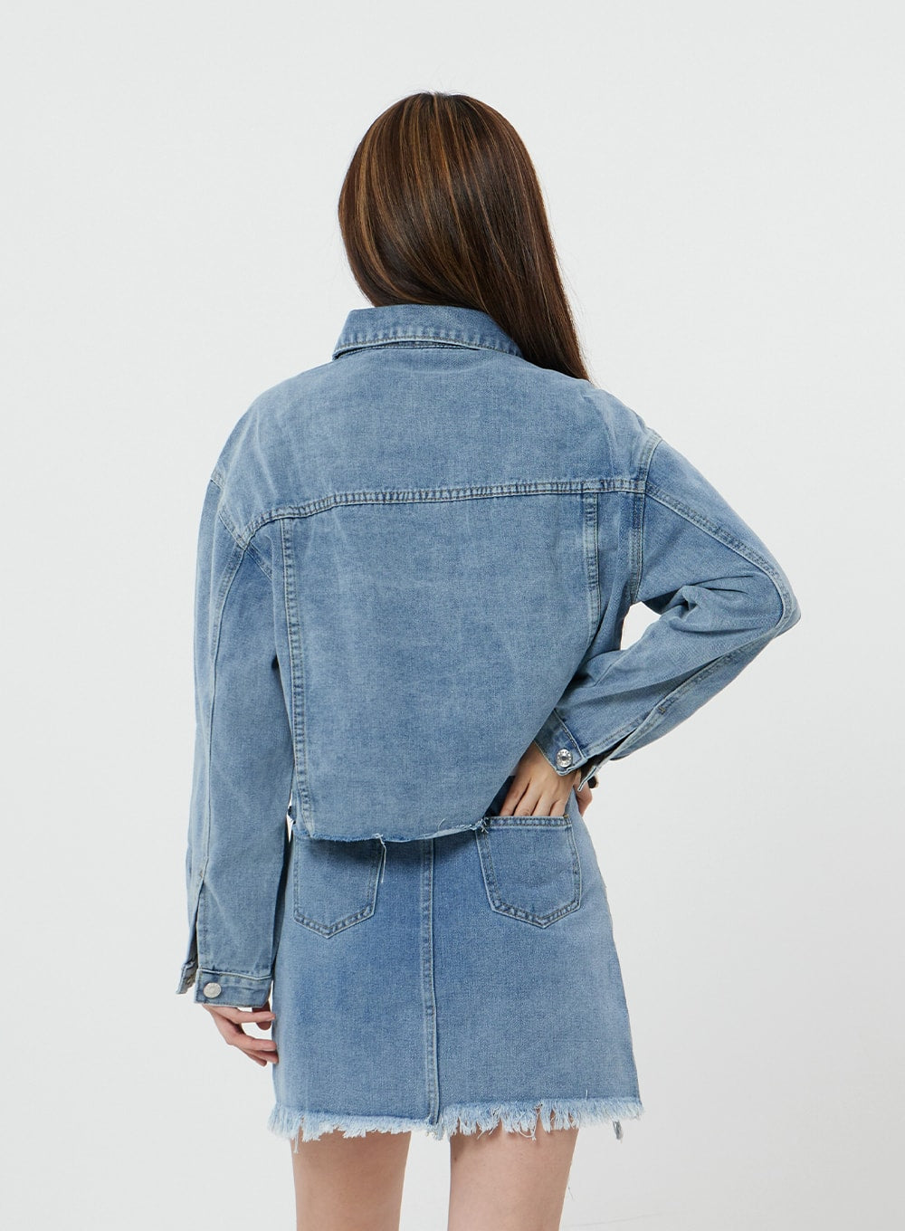 Sienna Crop Jeans Jacket CS21 in light blue, back view on model, clean back yoke seam and crop hem visible, worn with matching denim mini skirt with frayed hem.