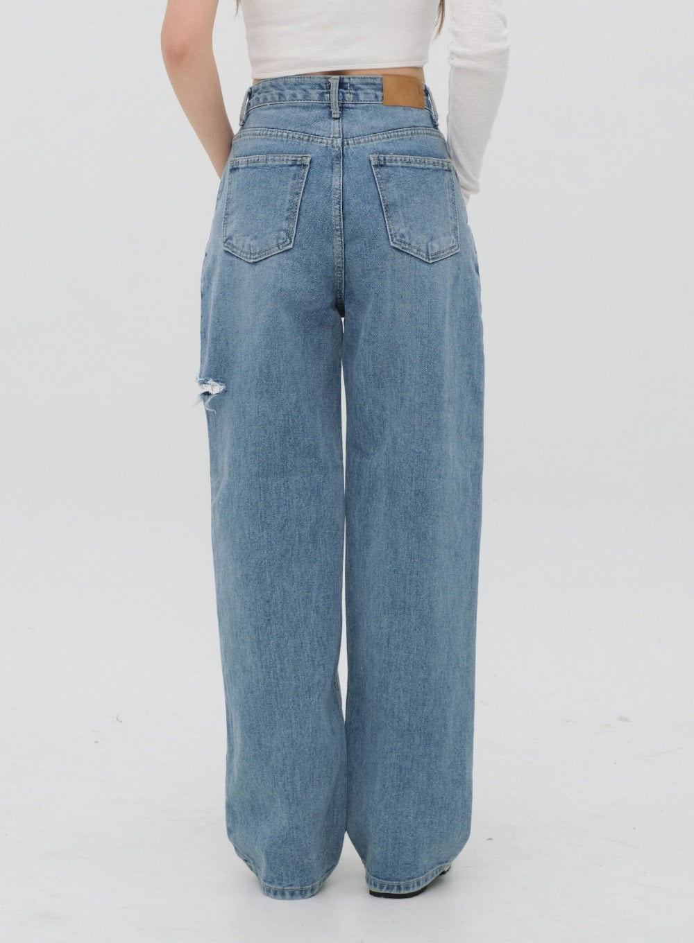 Torn Wide Leg Jeans C1002 in light blue, back full-length view on model, five-pocket construction with leather patch label, ripped thigh detail and wide straight leg.