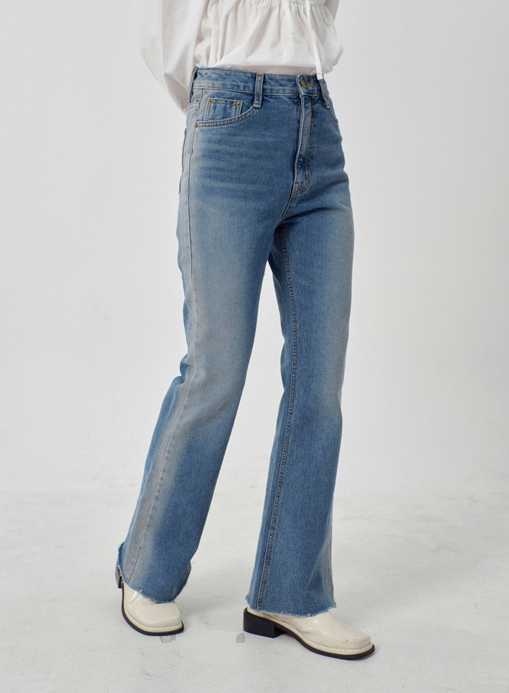 Light Washed Bootcut Jeans OD27 in light blue, side close-up from hip to hem on model, high-rise slim fit, washed cotton denim, bootcut flare with raw frayed hem detail and side seam visible.