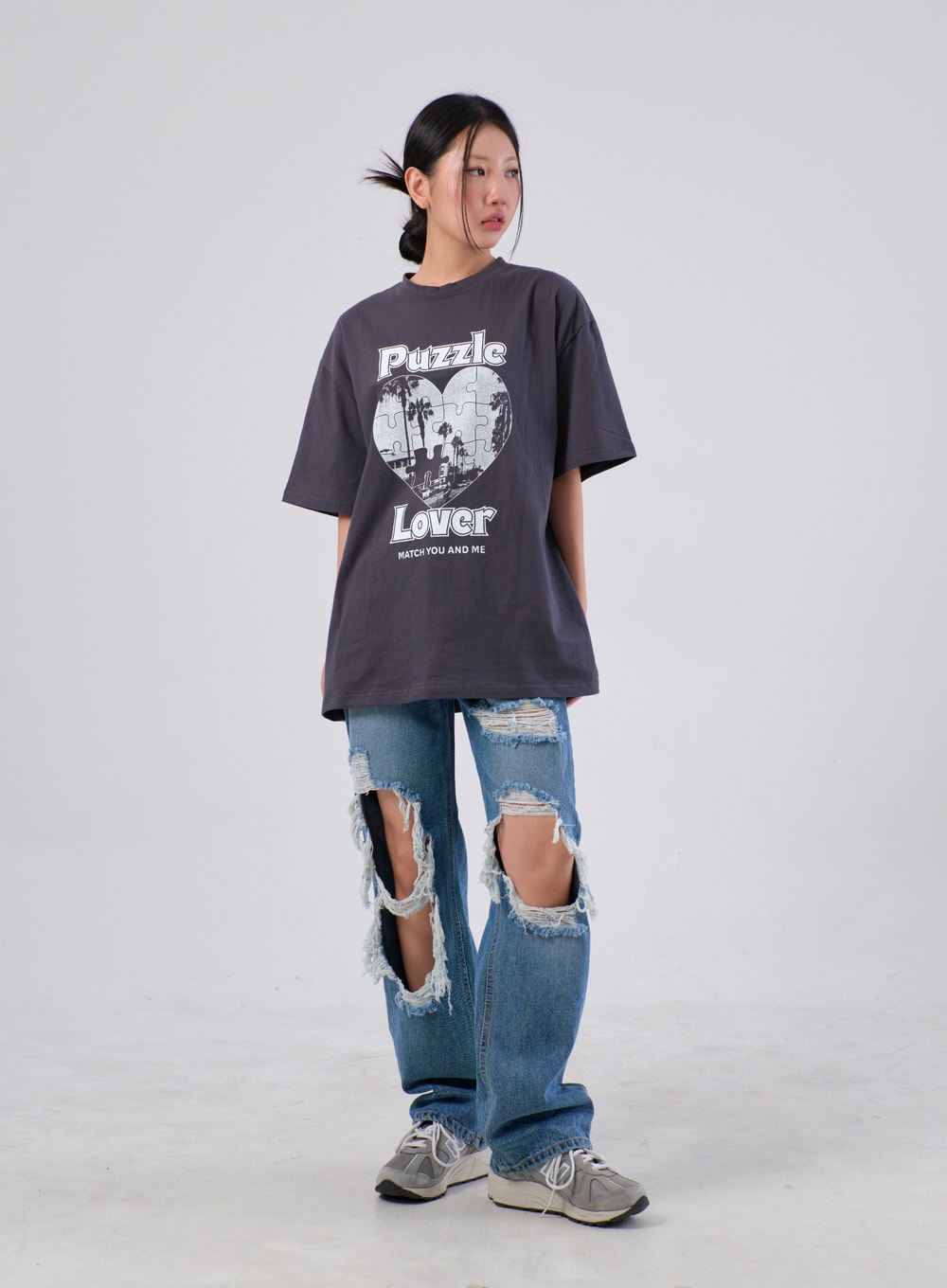Ripped Knee Jeans IA305 in medium blue, full-body front on model facing slightly left, wide-fit destroyed denim with open knee cutouts, layered under a charcoal graphic tee and sneakers.