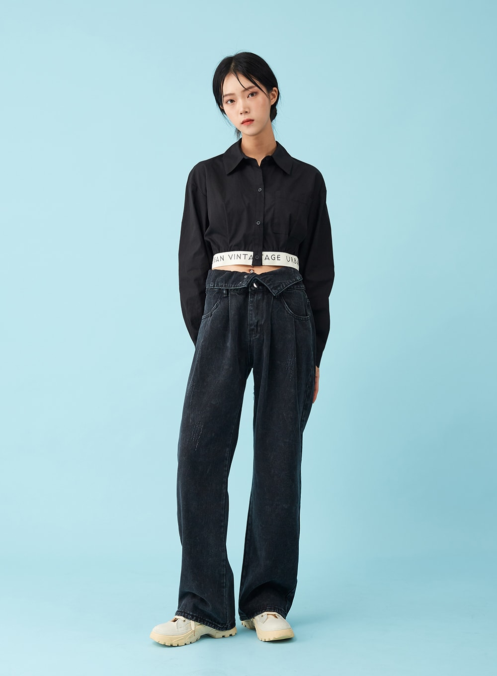 Four Buttoned Open Black Jeans CU8 in washed black, front full-body on model standing straight, hands in pockets, wide-leg denim with low open waistband and logo belt, paired with black crop shirt.