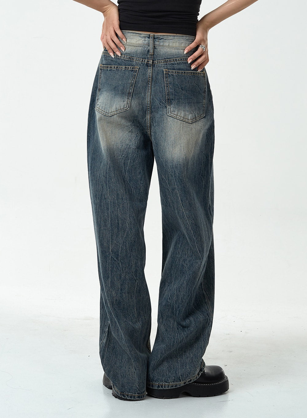 Washed Denim Pants CG10 in dark blue, back close-up from waist to hem on model, two back patch pockets with washed fading and heavy crinkle texture across seat and legs.
