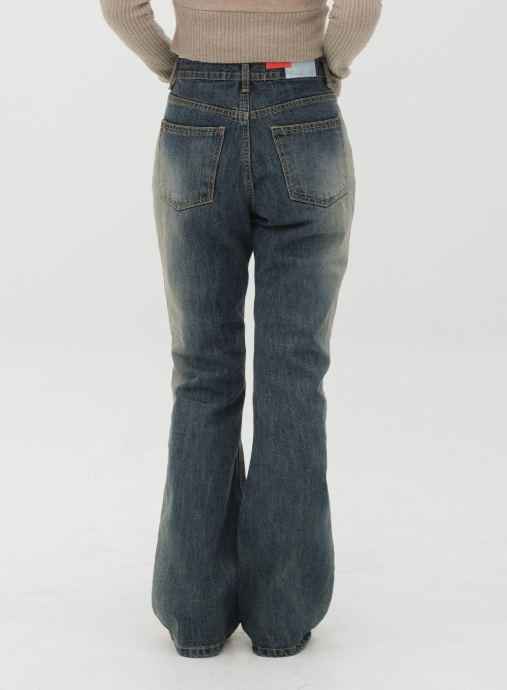 Boot Cut Jeans J20 in Dark Denim, back view on model, two back pockets with contrast stitching, gradation wash flared hem, brand label visible at waistband.