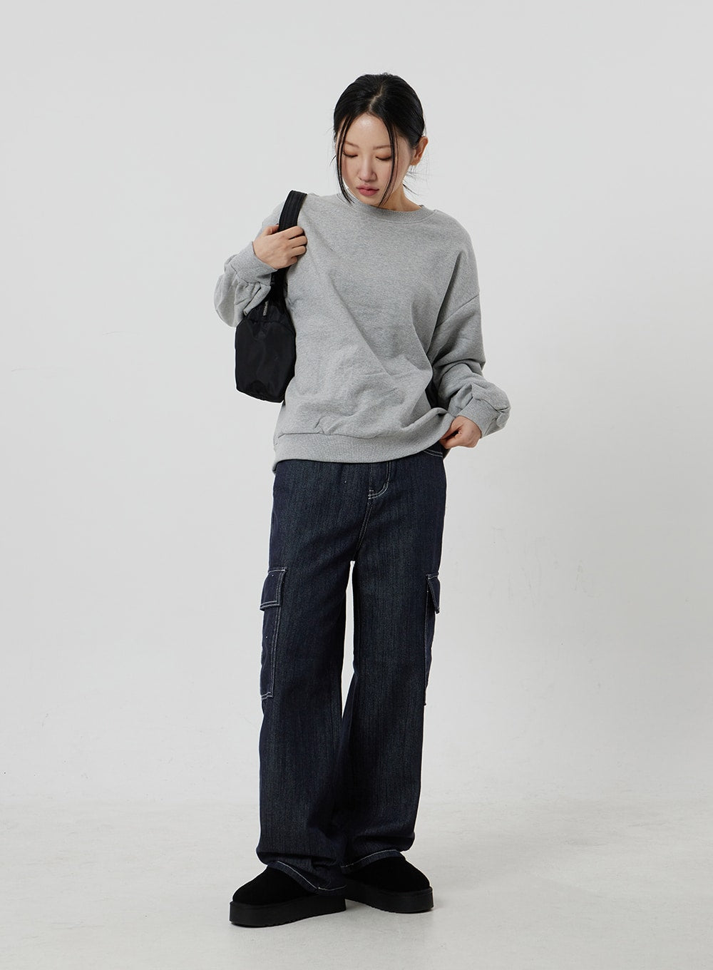 Wide Cargo Jeans CF302 in dark indigo, full-length front-angle on model looking down with black bag on shoulder, wide-fit denim with white-stitch cargo pockets, relaxed casual fit.
