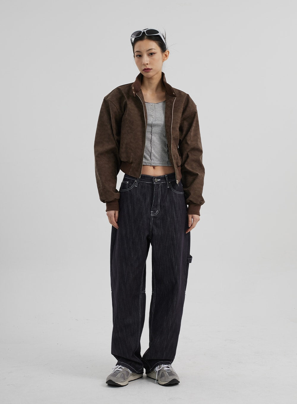 Mid-Rise Baggy Jeans CF307 in dark indigo, full-body front view on model, wide-fit cotton denim with carpenter seam detail, worn with open brown bomber and grey crop top.