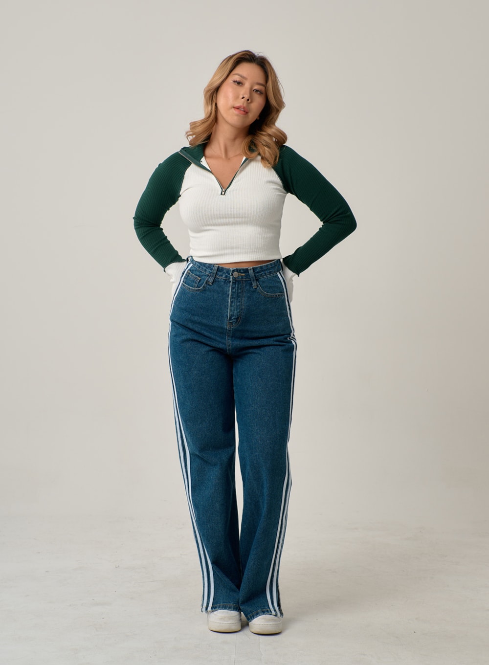 Side Stripes Straight Leg Jeans IN22 in mid blue, front full-length shot on model with hands on hips, high-rise wide-leg cotton denim, three white side stripes, sporty casual look with crop top.