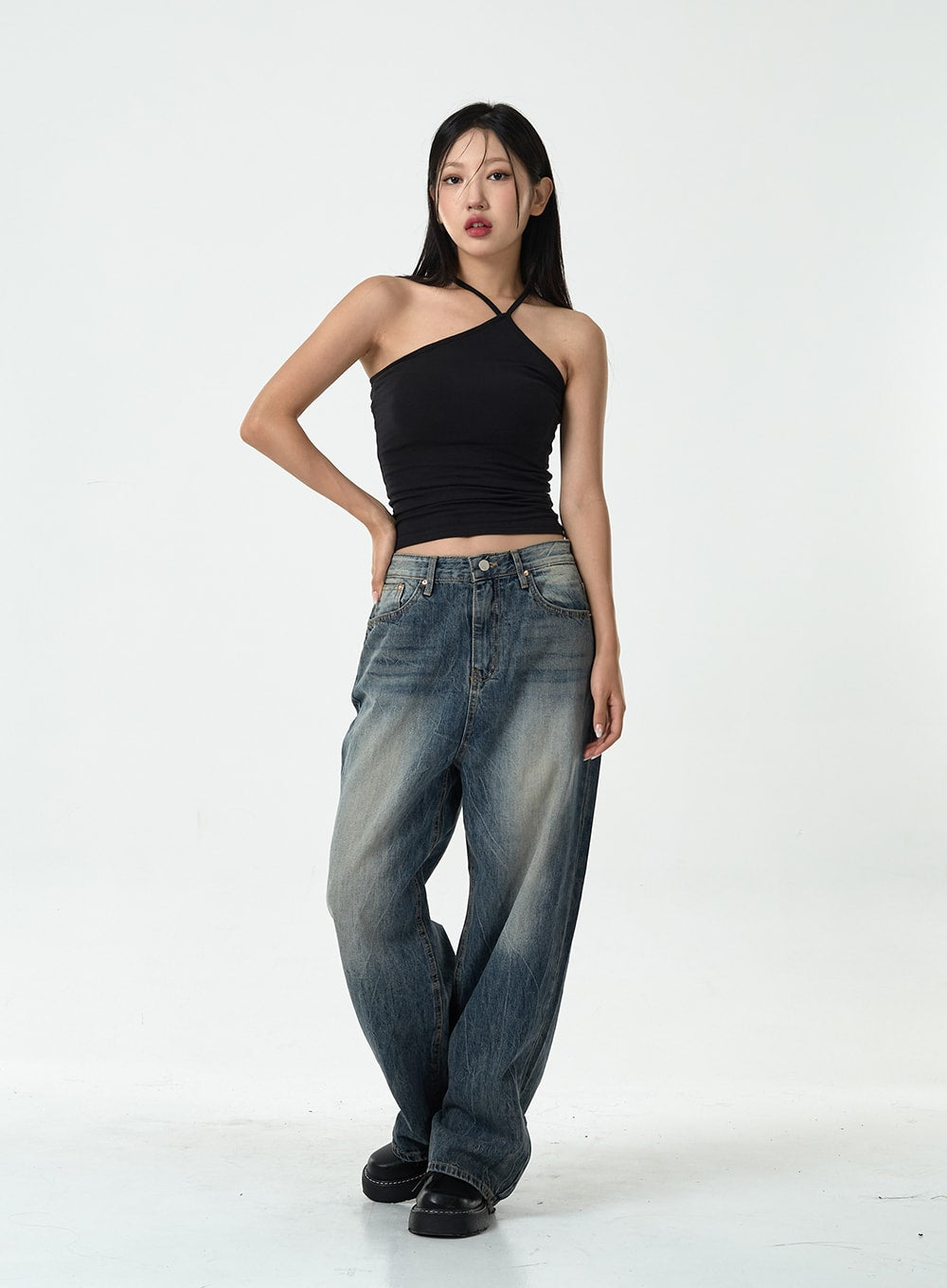 Washed Denim Pants CG10 in dark blue, full front view on model with hand on hip, wide-leg washed denim with sun-faded tonal gradient, casual pose, styled with black halter top.