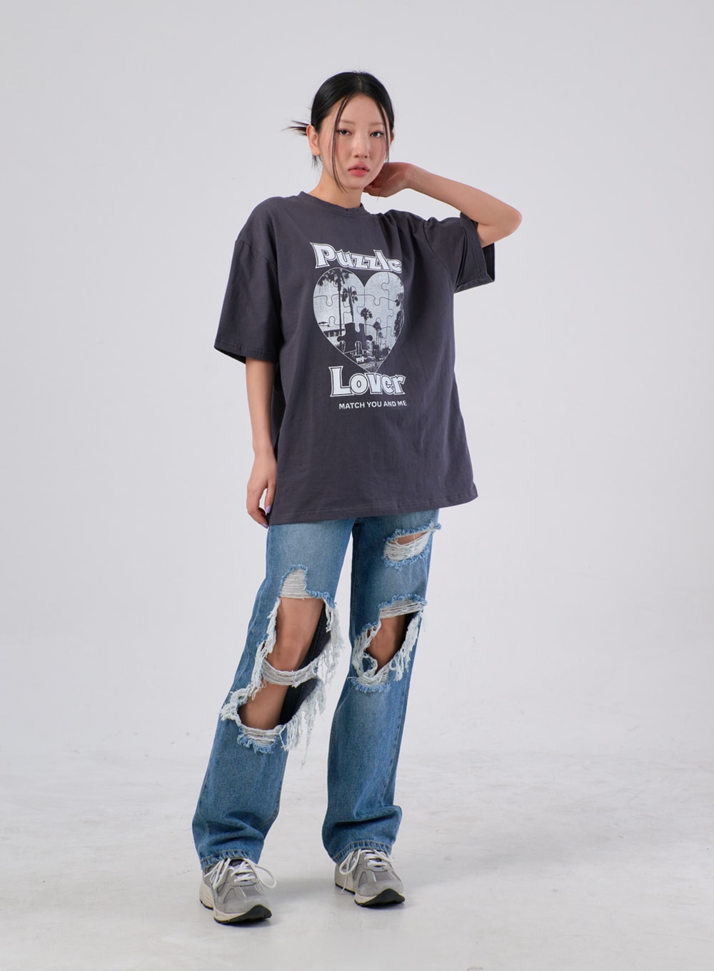 Ripped Knee Jeans IA305 in medium blue, full-body front on model with hand raised, wide cotton denim featuring large ripped knee holes with heavy fraying, styled with oversized charcoal tee.