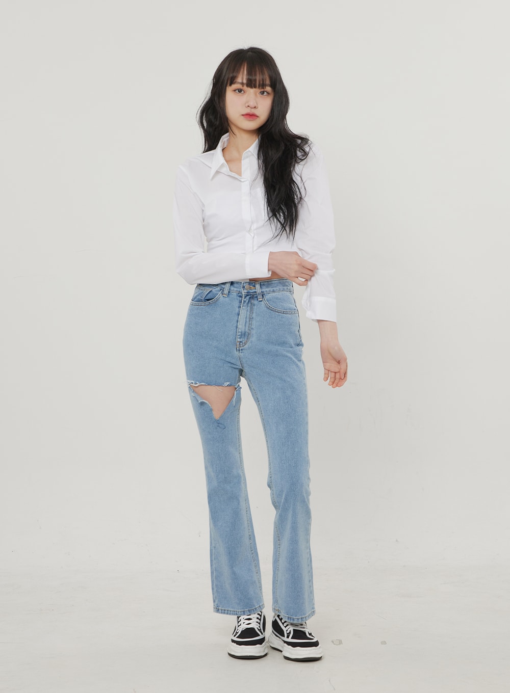 Ripped Bootcut Jeans BF306 in light blue, front full-body on model with relaxed pose, large destroyed cutout at thigh visible, slim bootcut leg, styled with white crop shirt.