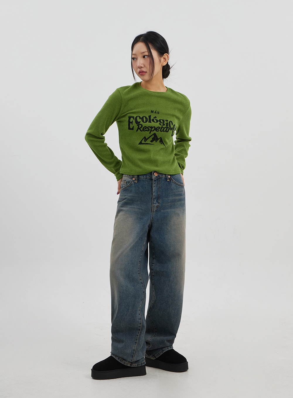 Mid-Rise Baggy Jeans Unisex CJ330 in vintage blue, full-body three-quarter front view on model standing straight, wide-leg denim with vintage fade, paired with green knit top.
