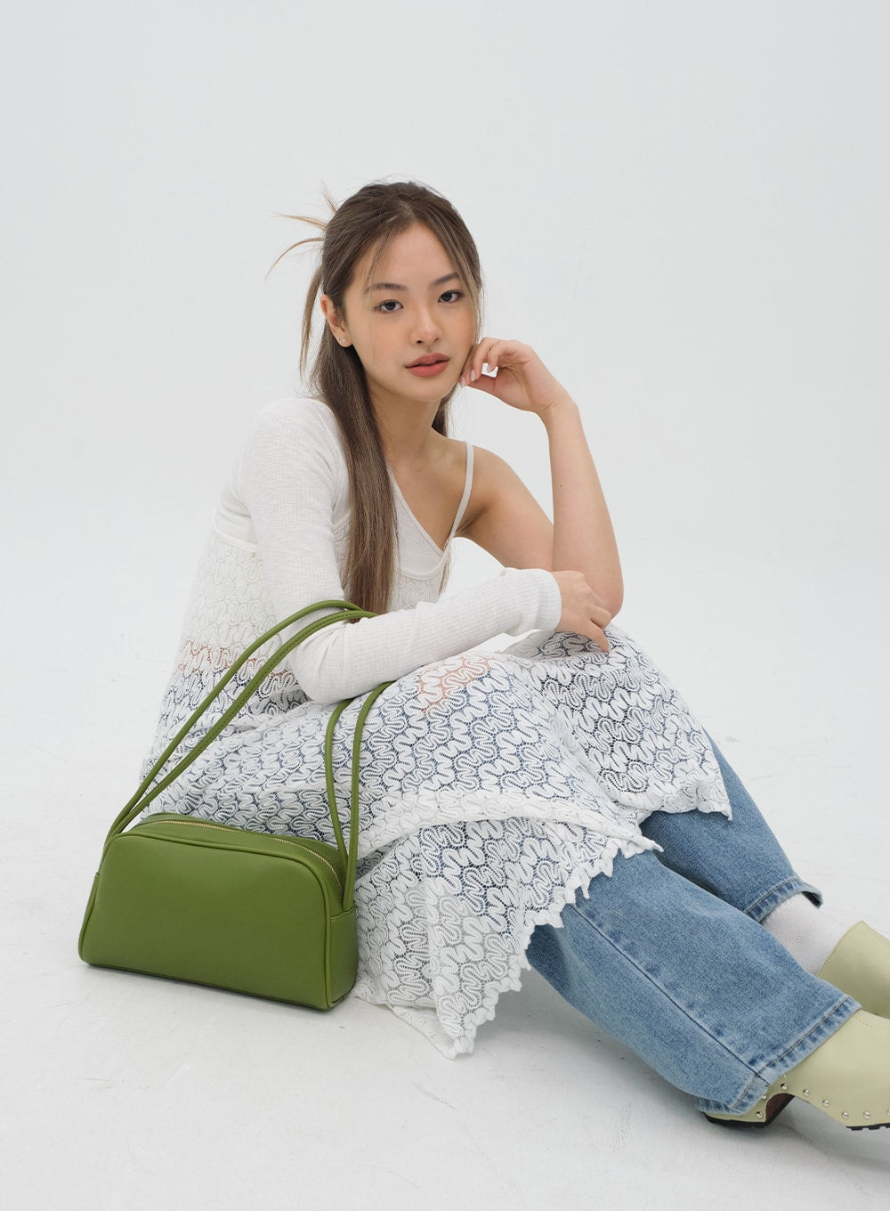 Torn Wide Leg Jeans C1002 in light blue, seated floor-level shot on model, wide-leg hem and ripped knee detail visible, styled with white lace layer and green bag.