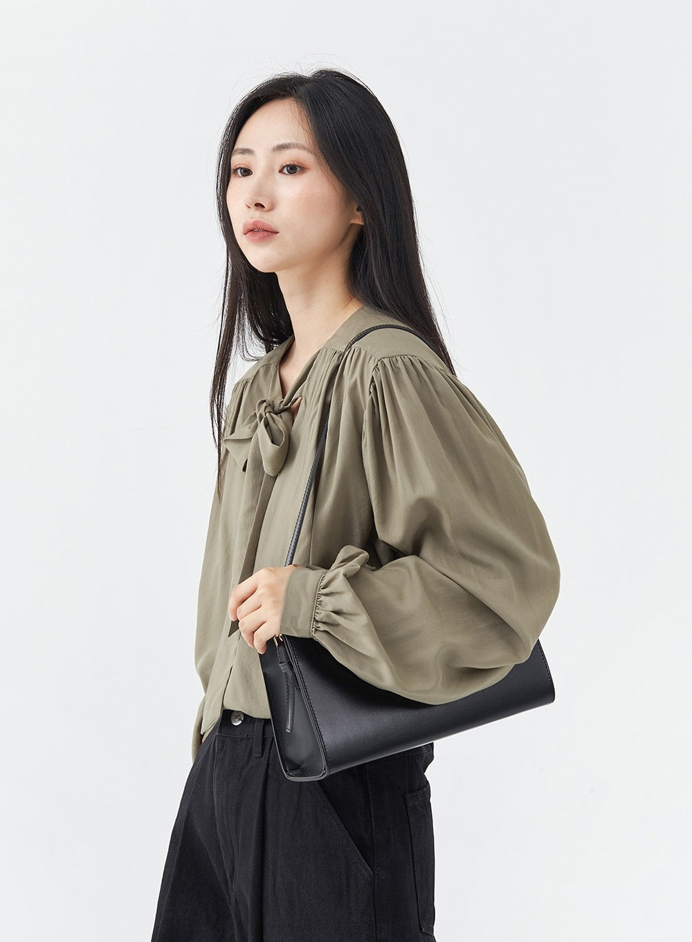 Pintuck Black Jeans OG18 in black, upper-thigh-to-waist side close-up on model, wide-fit cotton with pintuck detail visible, styled with olive blouse and black shoulder bag.