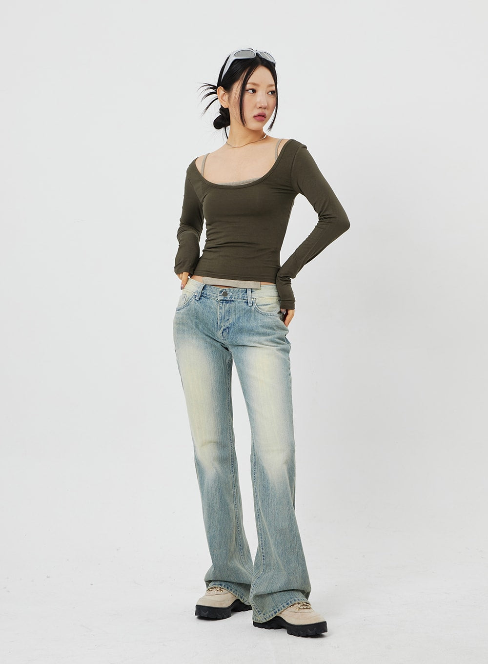 Low Rise Bootcut Jeans CF315 in light blue, front full-length shot on model with hand on hip, low-rise slim bootcut, warm yellow wash fade at thighs, olive crop top styling.