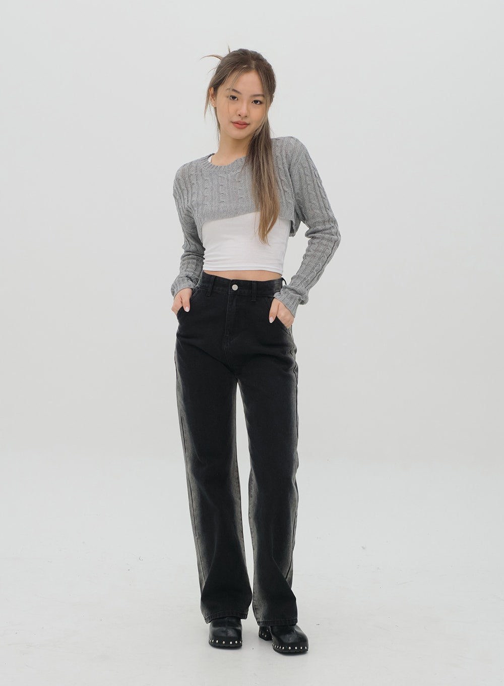 Black Jeans C1002 in washed black, full-body front shot on model, hands in pockets, wide straight-leg fit, high rise, faded panels, paired with grey cable-knit crop and white top.