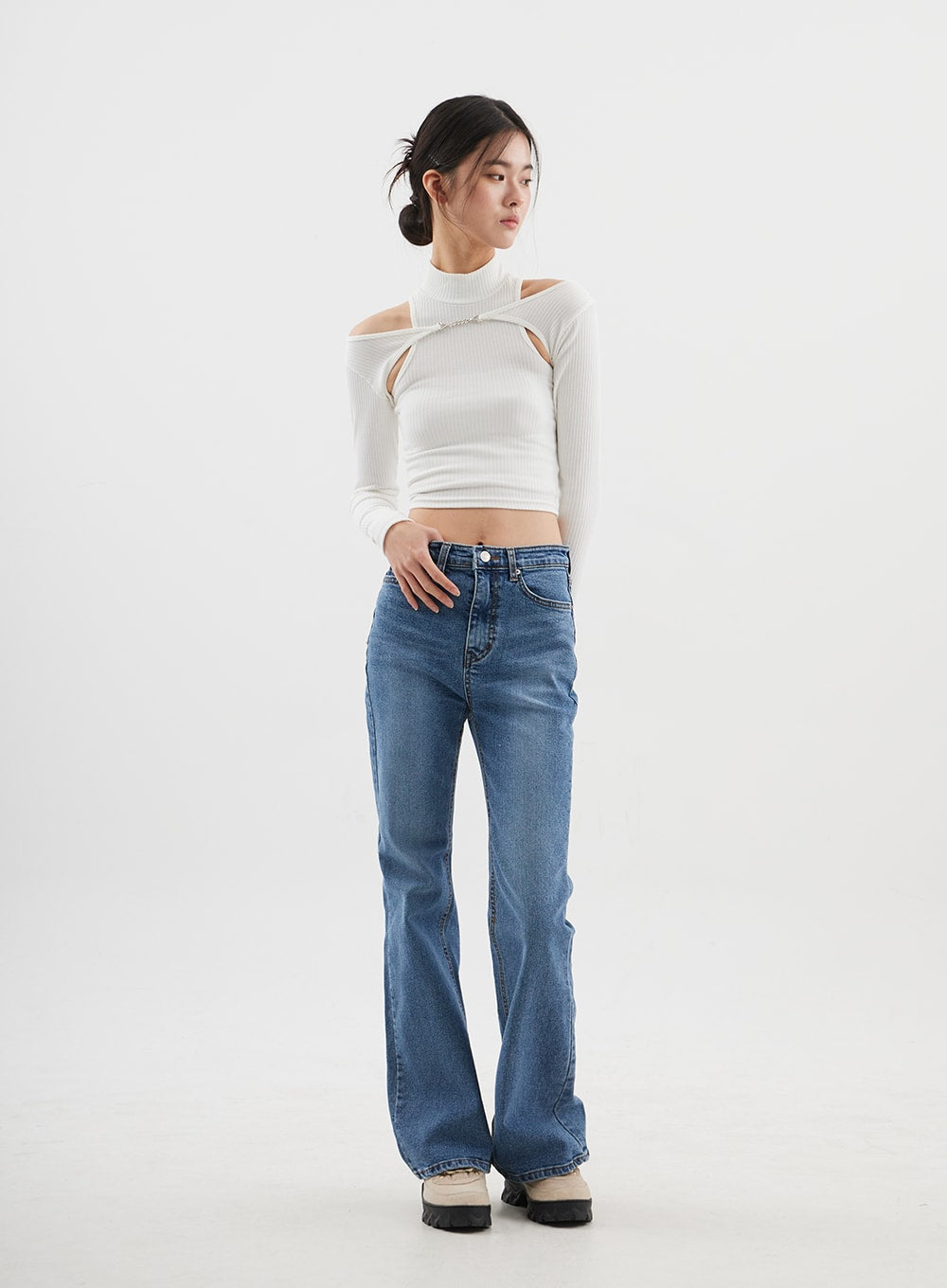 Slim Fit Bootcut Jeans CJ311 in medium blue, full-length front view on model gazing down, slim fit through thigh with gentle flare, cotton-spandex blend, styled with white cut-out turtleneck.