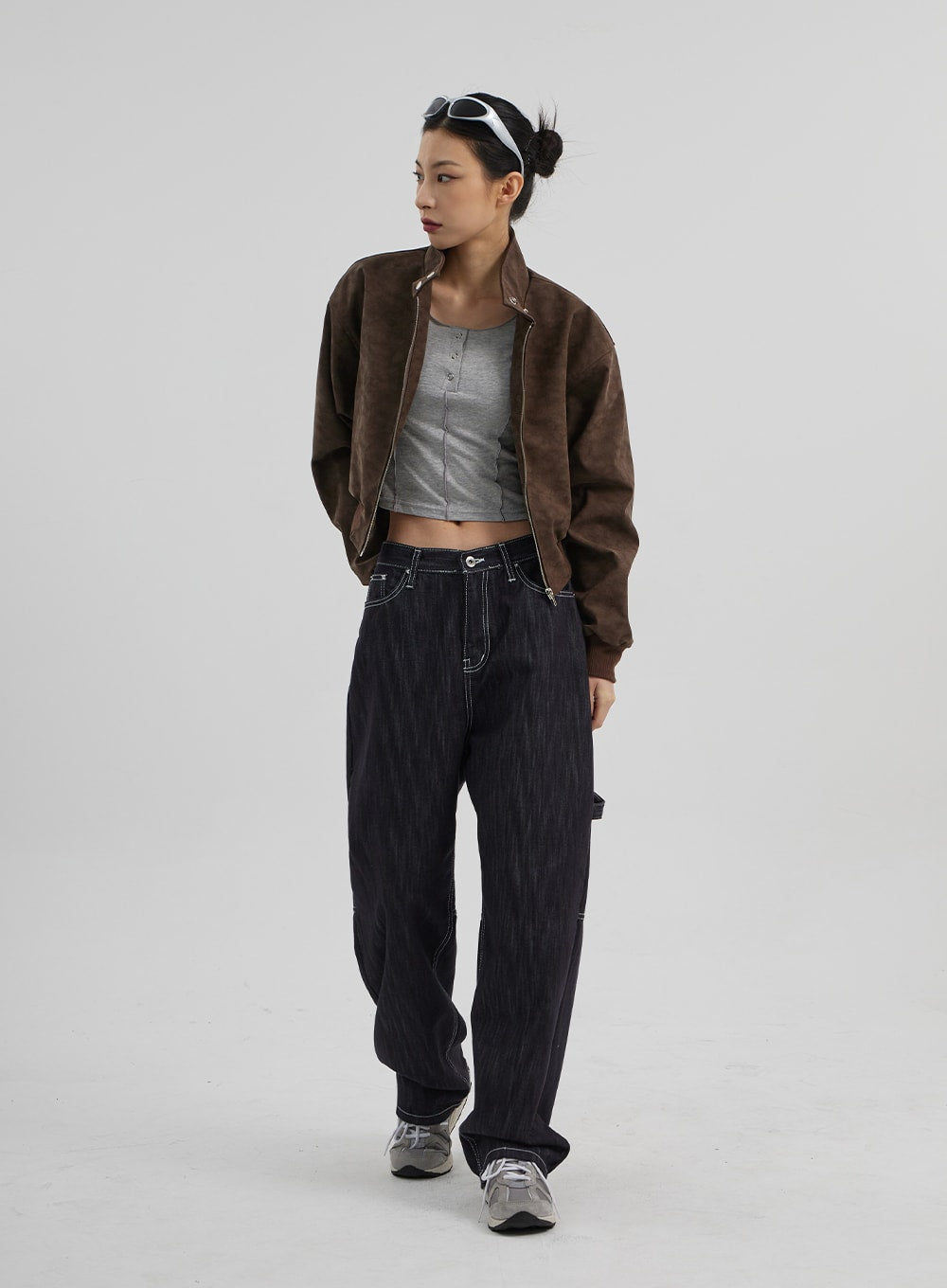 Mid-Rise Baggy Jeans CF307 in dark indigo, full-body slight side angle on model walking, wide-leg carpenter denim with contrast topstitch, layered with open brown jacket and grey top.
