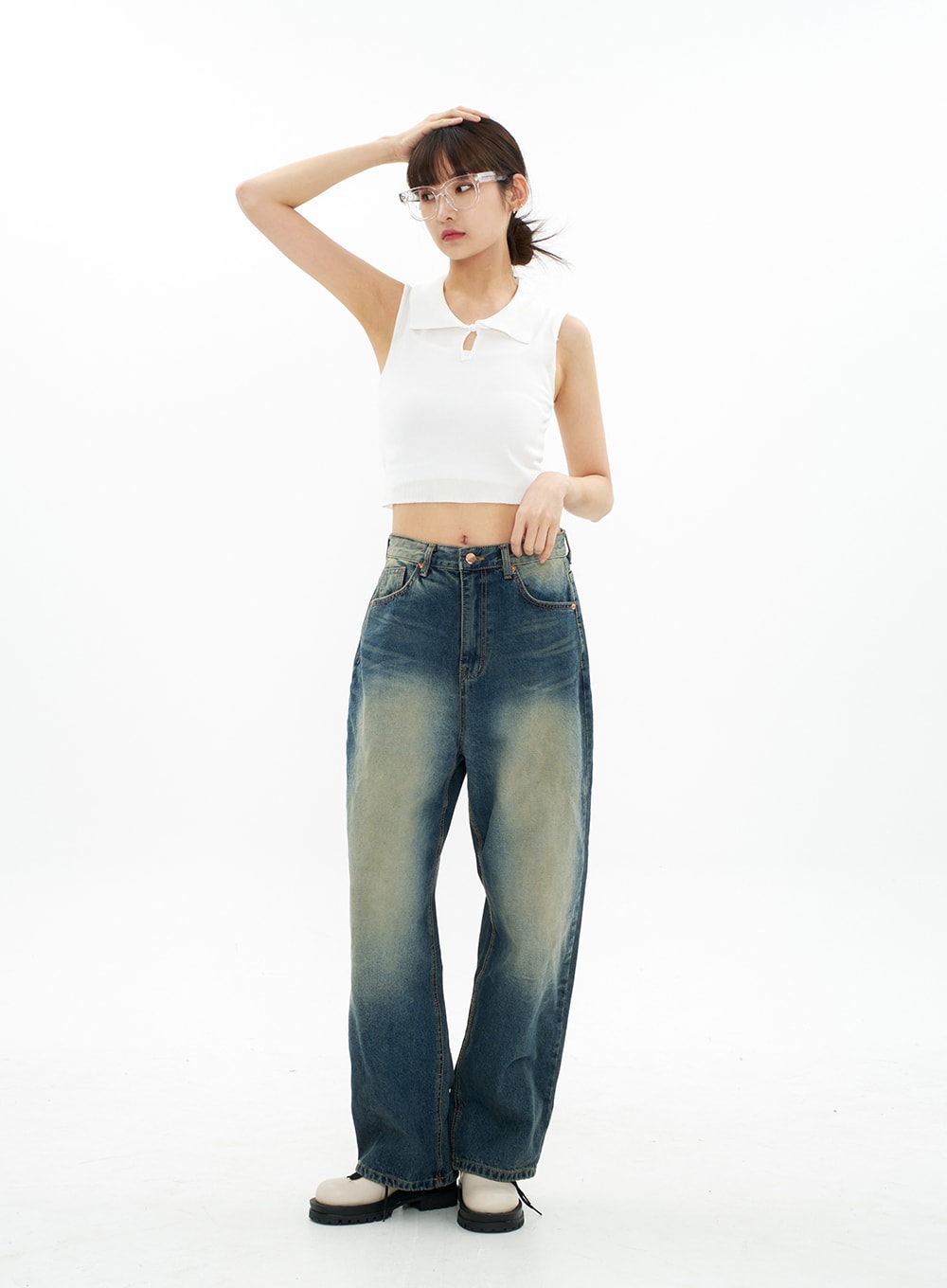 Bleached Wide Leg Denim Pants CA07 in vintage blue, full-body front view on model with hand raised to hair, wide-fit long cotton denim with heavy bleach wash, paired with white crop top.