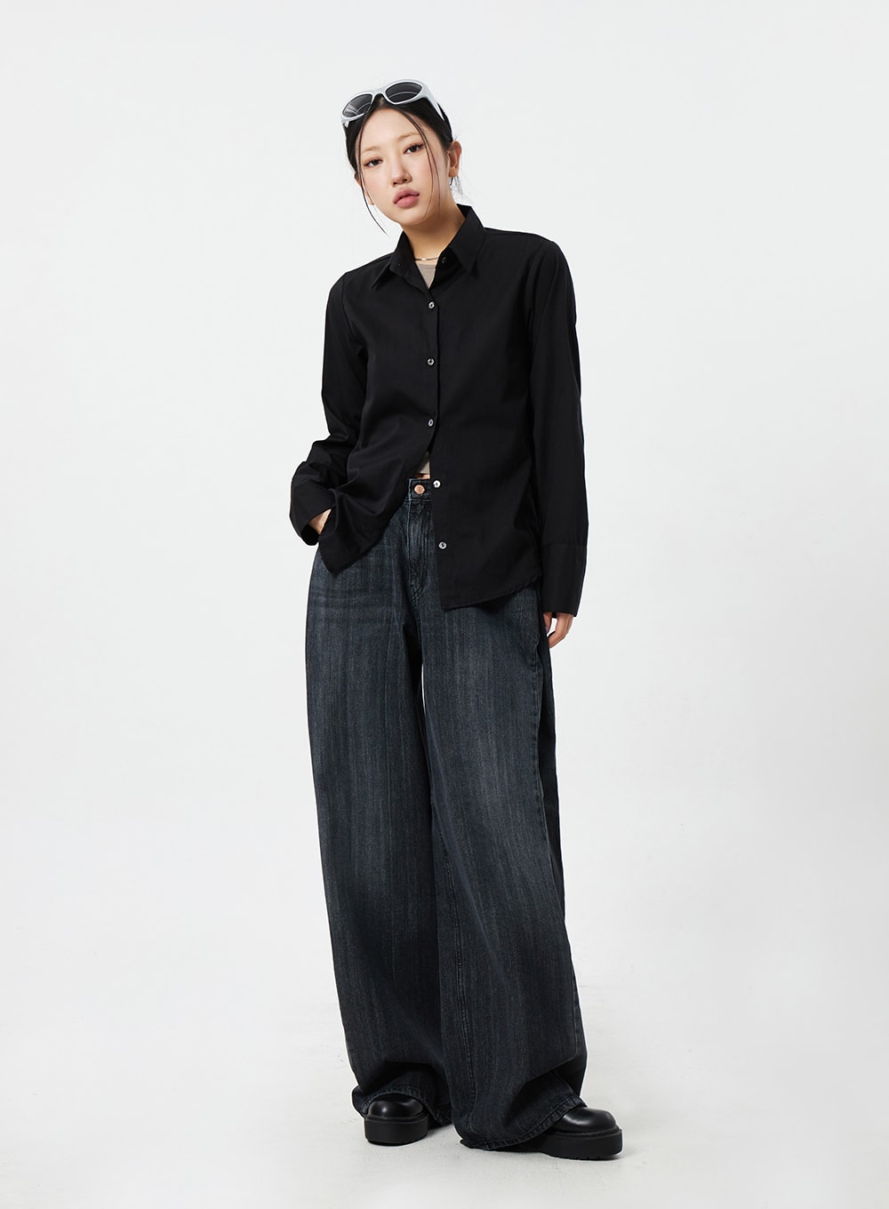 Mid-Rise Baggy Jeans CM324 in washed black denim, full-length three-quarter front view on model looking sideways, street-style baggy silhouette with black shirt and chunky platform shoes.