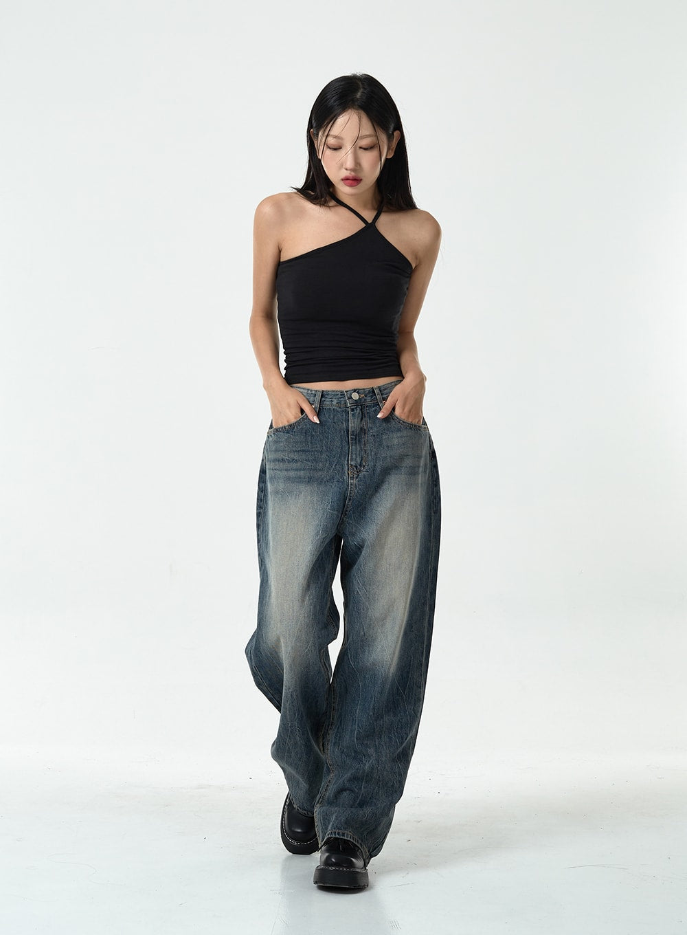 Washed Denim Pants CG10 in dark blue, full front view on model walking with gaze down, wide-leg washed cotton denim pooling slightly at hem, hands in front pockets.