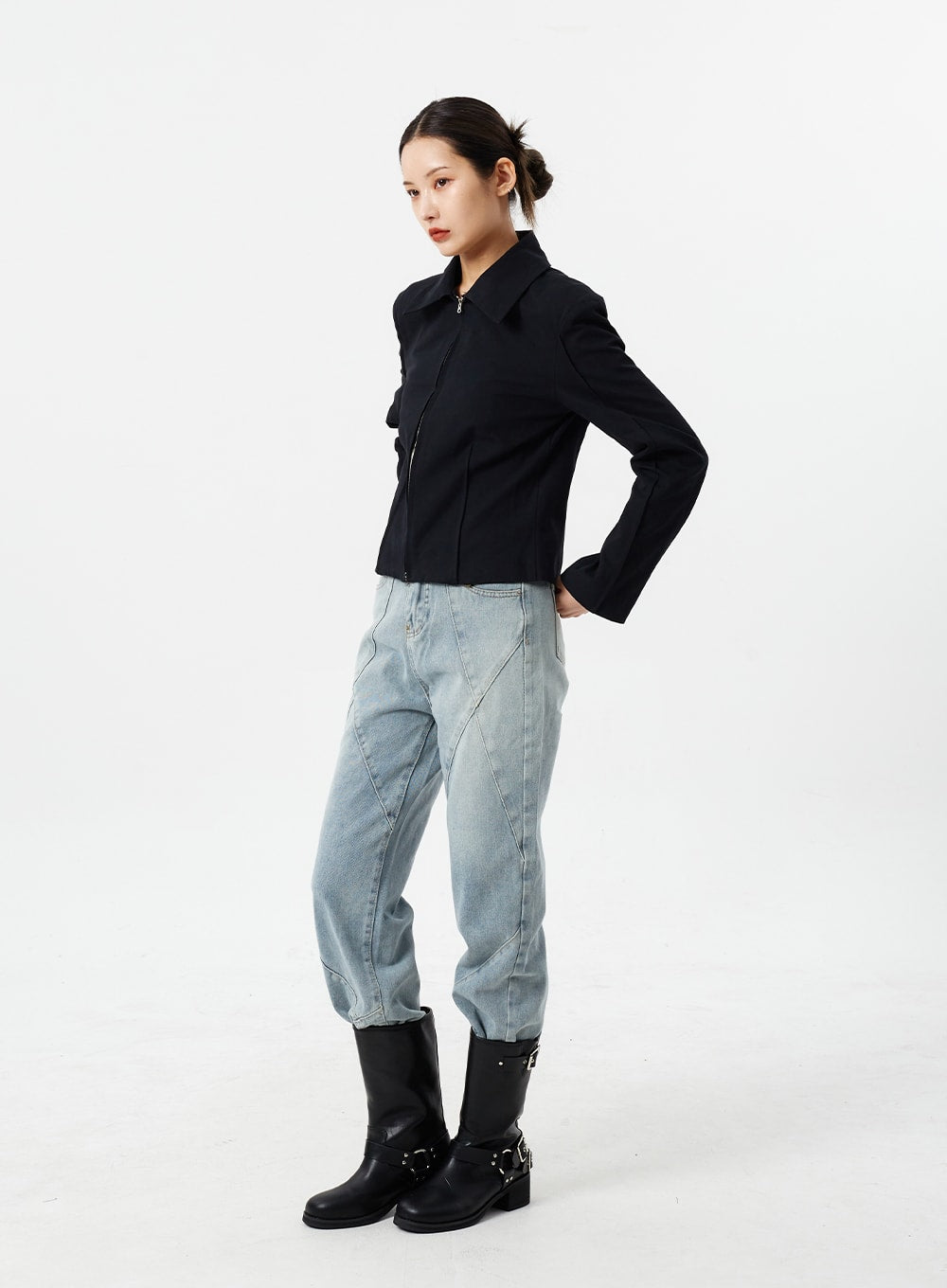 Light Wash Straight Leg Jeans CM307 in light blue, full-body side view on model, straight-fit washed cotton with visible geometric seams along leg, styled with black zip jacket and tall boots.