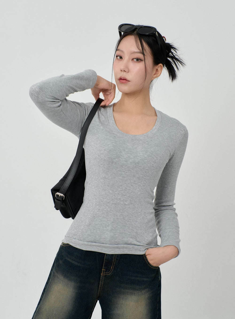 Vintage Washing Baggy Jeans ID23 in dark indigo, mid-body front close-up on model, vintage yellow-fade waistband detail, paired with grey scoop-neck top, black shoulder bag and sunglasses.