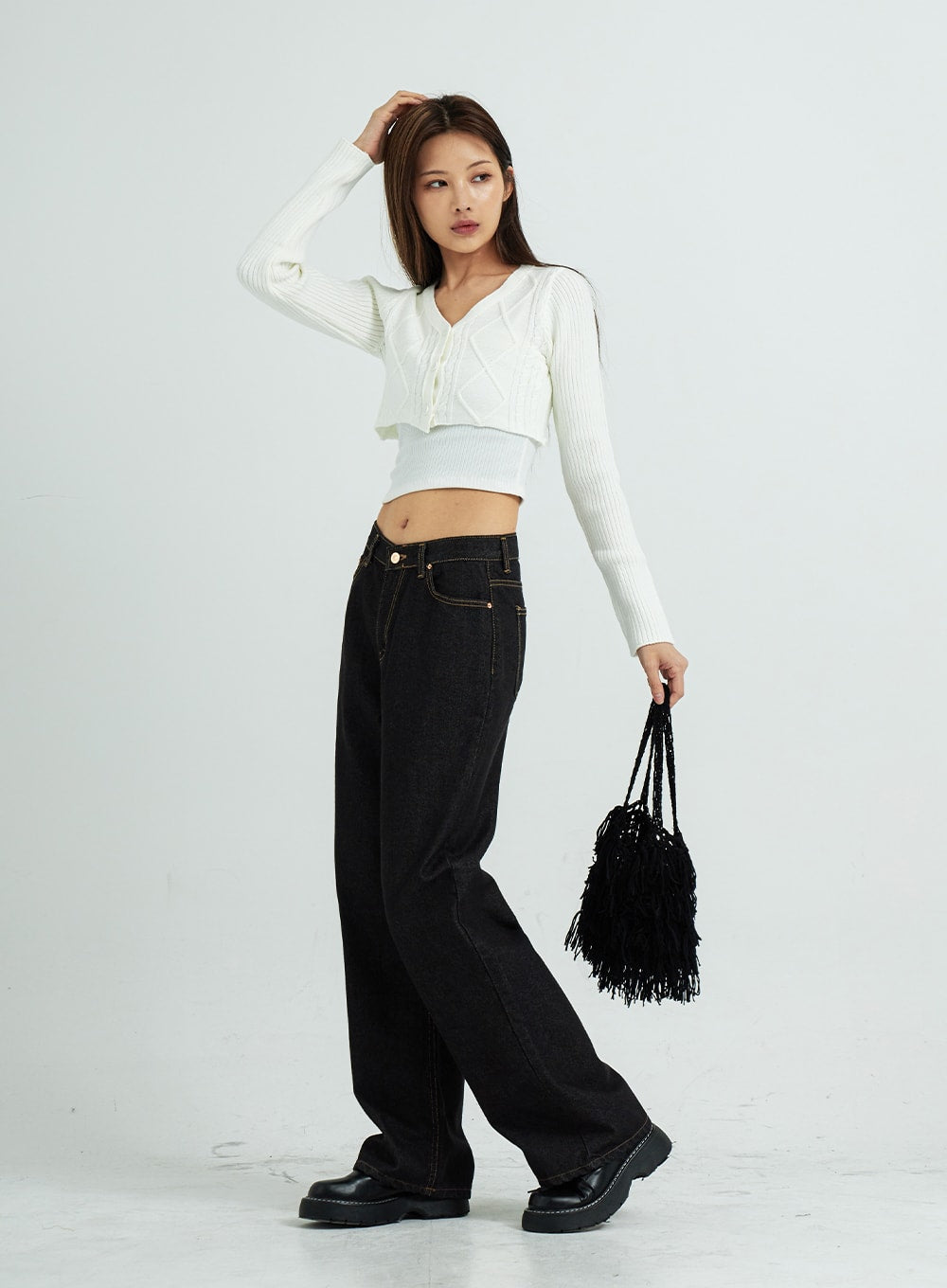 Pepe Wide Pants CS15 in black, full-body side-angled view on model, wide-fit cotton denim with gold topstitching, paired with white cropped knit and black fringe bag.