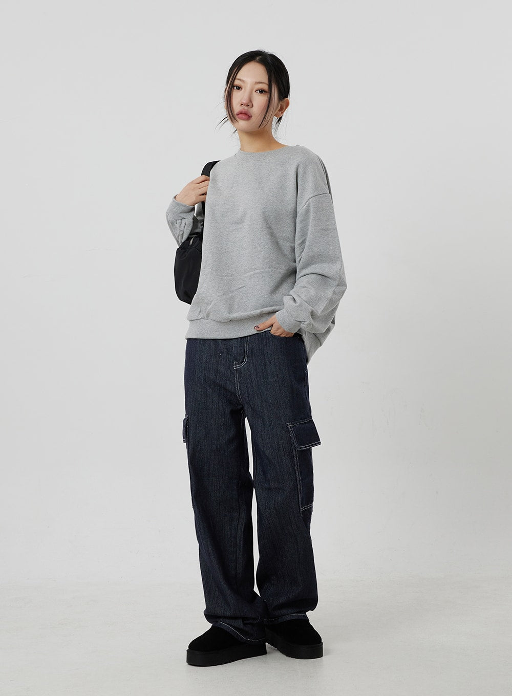 Wide Cargo Jeans CF302 in dark indigo, full-length three-quarter front view on model with black bag, wide-fit cotton denim with contrast-stitch cargo pockets, styled with grey sweatshirt.