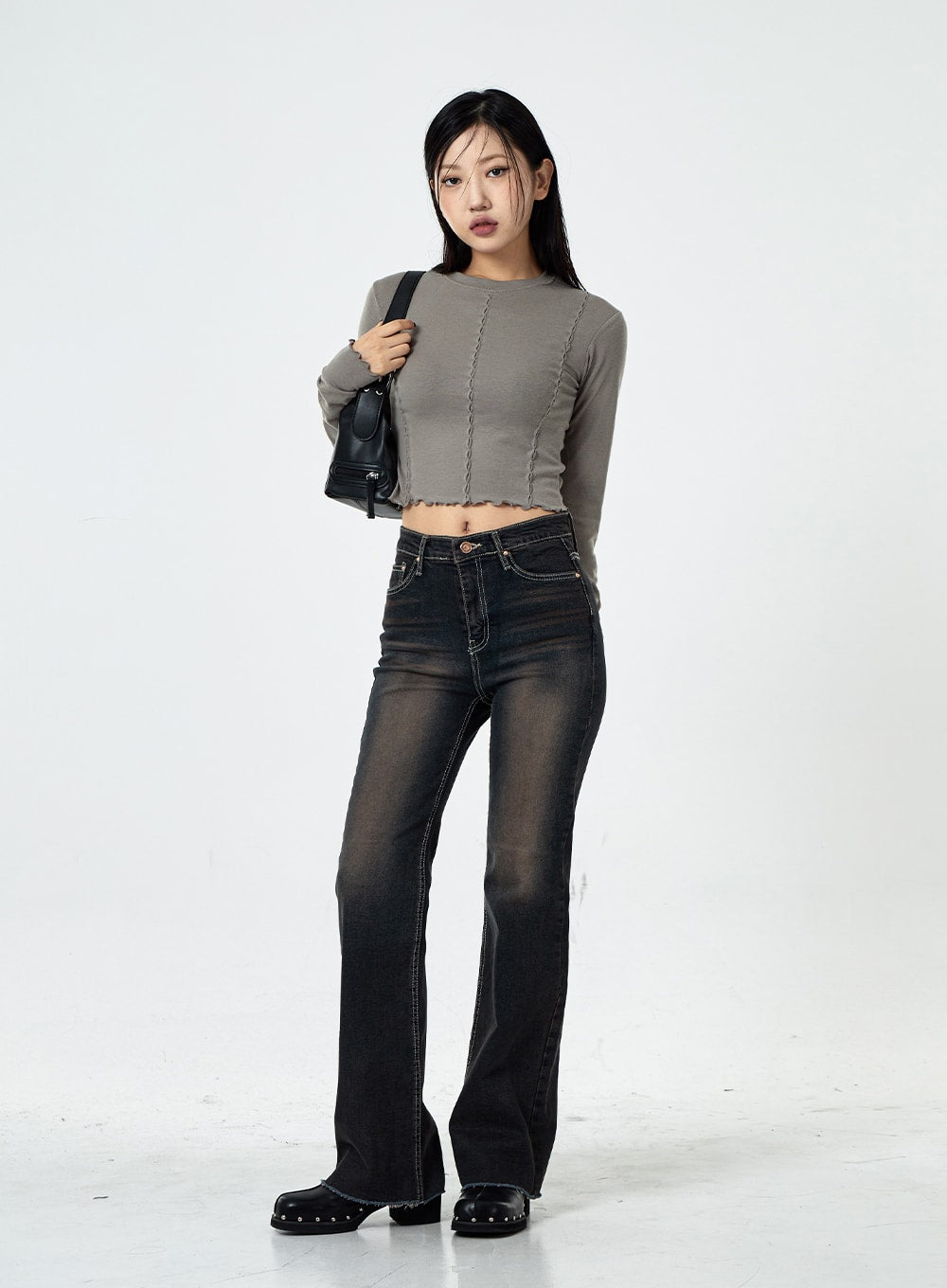 Basic Washed Bootcut Jeans CS07 in black washed denim, full-length front view on model, slim high-rise bootcut silhouette, washed fade detail, paired with grey long-sleeve crop top and mini bag.