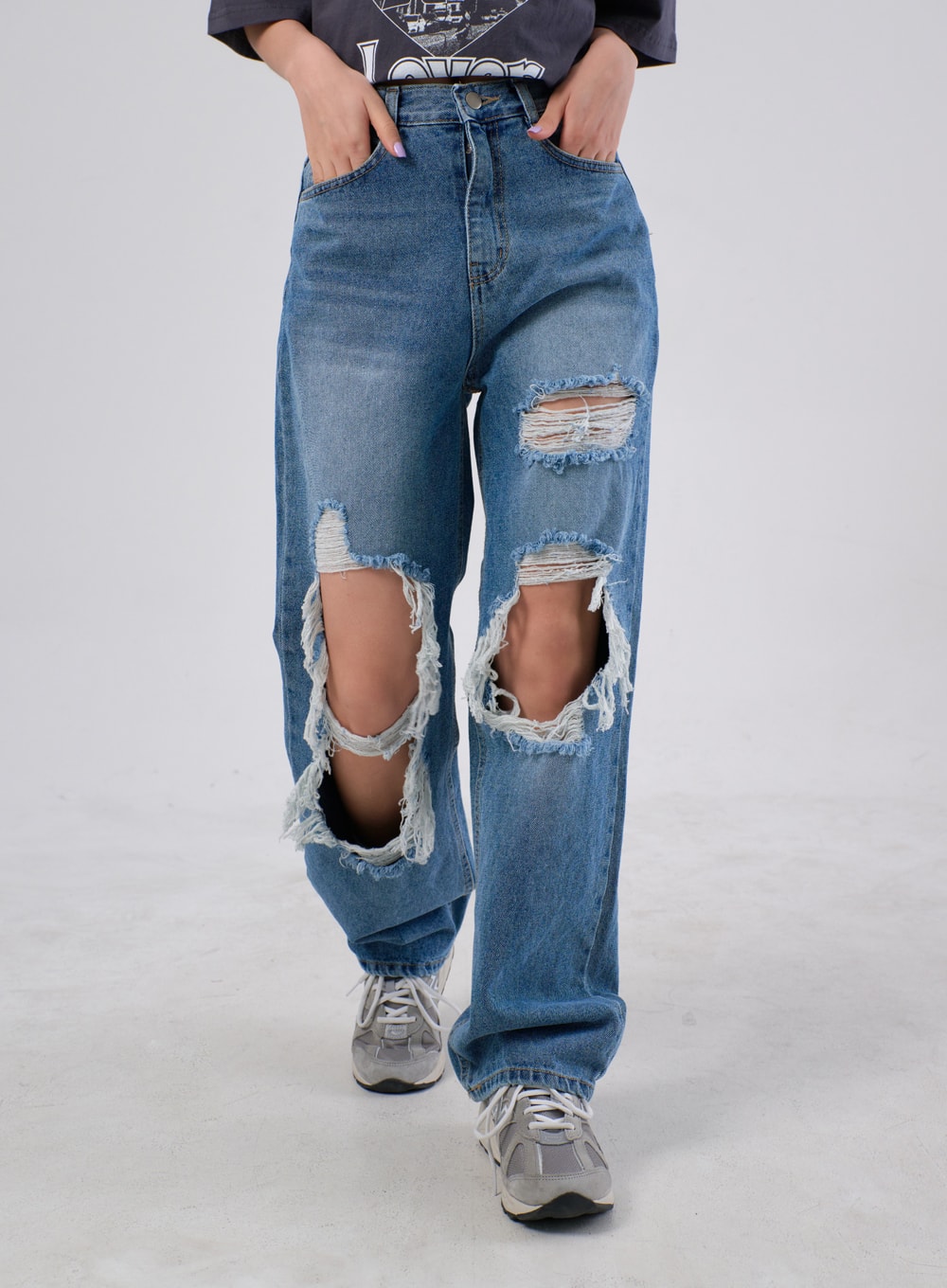 Ripped Knee Jeans IA305 in medium blue, front waist-to-hem close-up on model walking, highlighting multiple stacked destroyed rips and thick frayed edges across both knees.