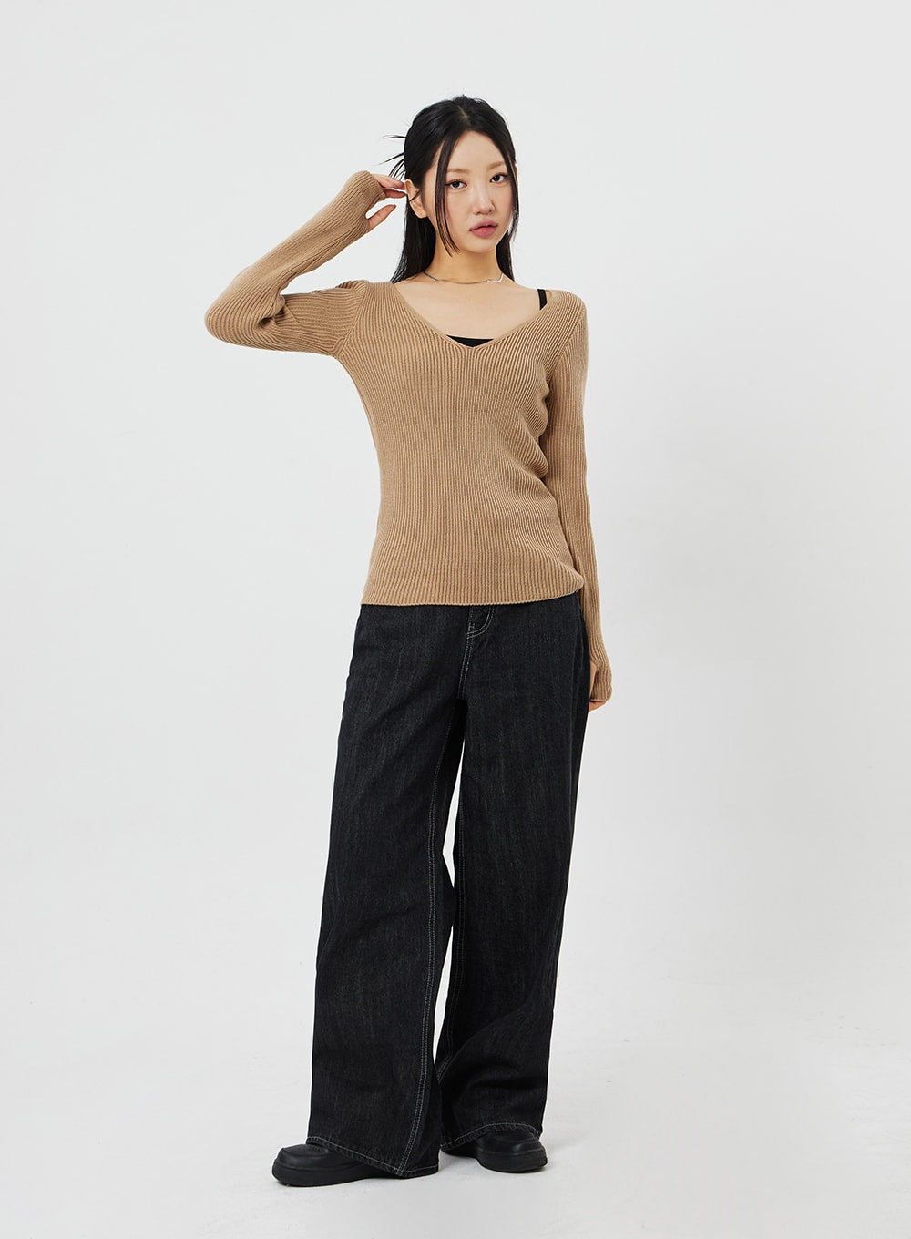 Straight Leg Jeans CF315 in black, full-body slight angle view on model with hand raised, wide-fit straight-leg denim, acubi style, paired with camel ribbed knit top.