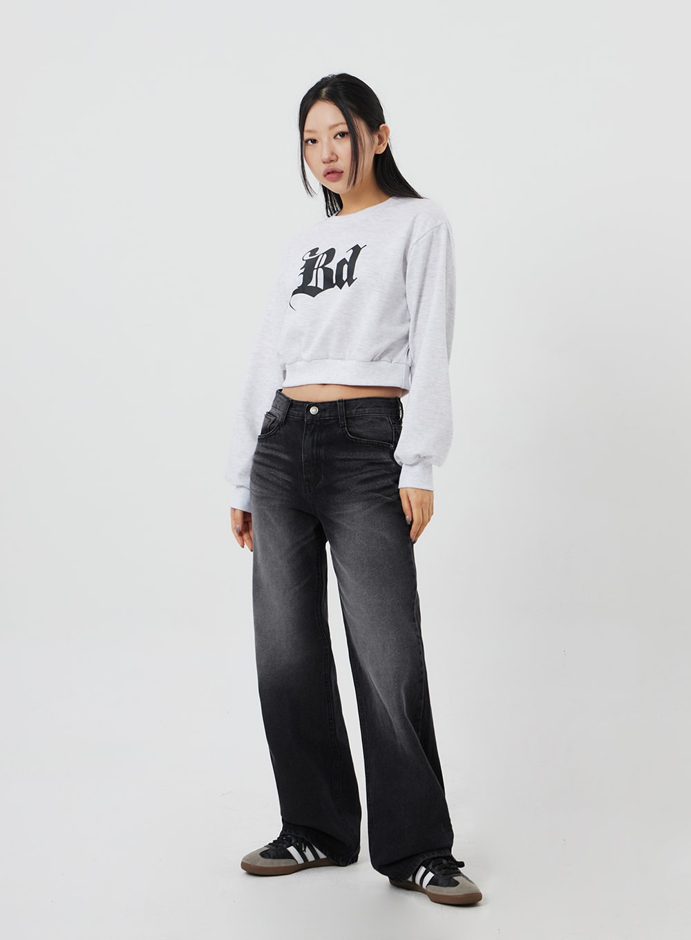 Mid-Rise Bootcut Jeans CF327 in black, full-body three-quarter front on model, slight turn showing leg width and bootcut sweep, faded washed denim, styled with crop sweatshirt.