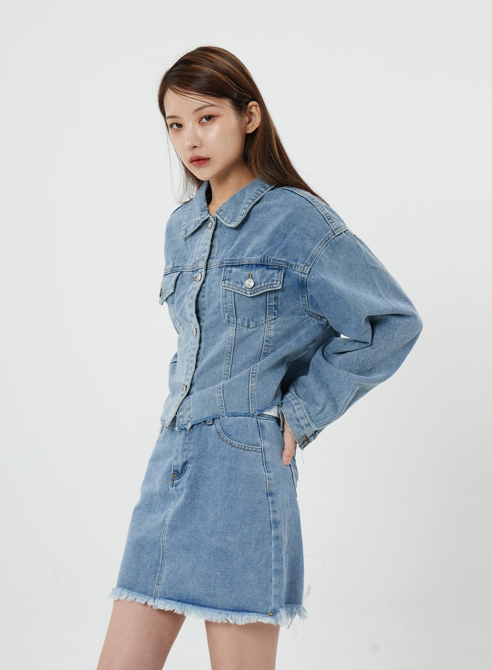 Sienna Crop Jeans Jacket CS21 in light blue, side view on model, structured shoulder seam and cropped length shown, paired with frayed-hem denim mini skirt.
