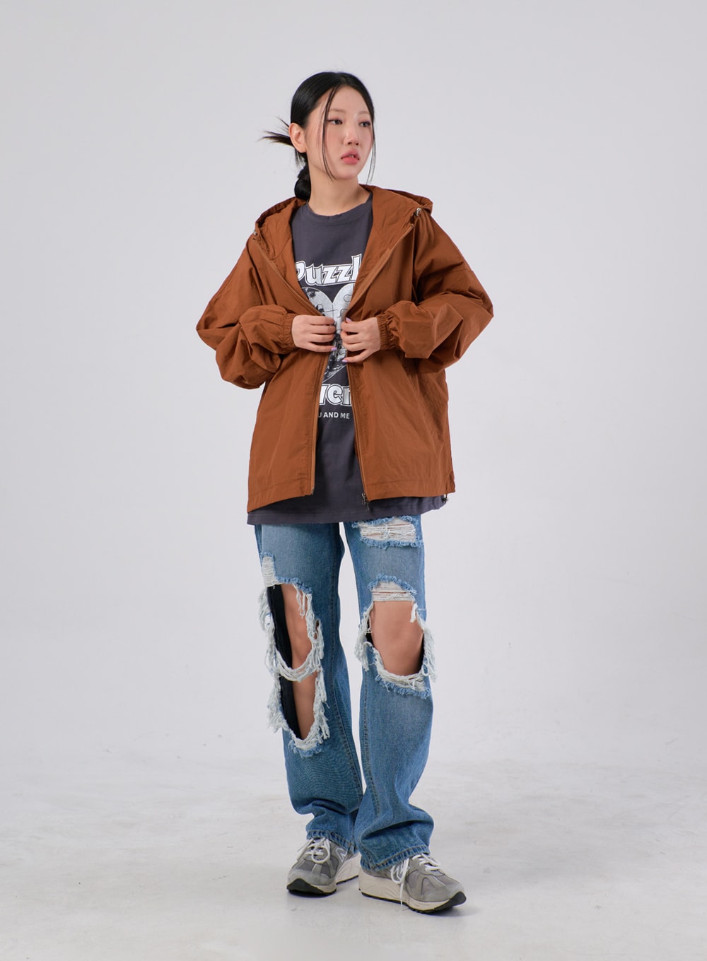 Ripped Knee Jeans IA305 in medium blue, full-body front on model, wide-fit destroyed denim styled with brown hooded windbreaker over grey graphic tee and grey sneakers, street look.