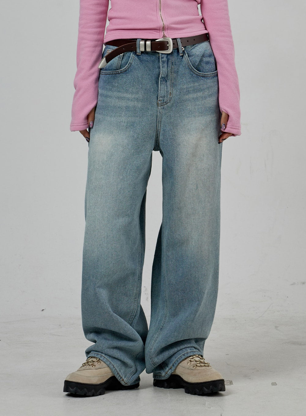 Light Wash Baggy Jeans Unisex CD26 in light blue, front lower-body close-up, wide-leg washed denim bunching over sneakers, visible fading across thighs and knees, belt detail at waist.