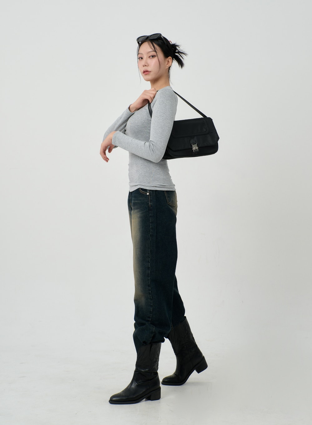 Vintage Washing Baggy Jeans ID23 in dark indigo, full-body side view on model carrying black shoulder bag, wide-fit leg with vintage wash gradient, black knee-high boots and sunglasses on head.