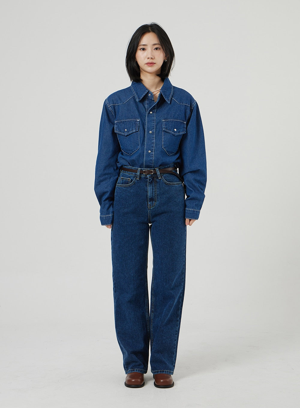 Basic Indigo Jeans OF310 in indigo, clean full-body front shot on model, wide-fit high-rise cotton denim with straight leg, belted, paired with denim shirt and brown boots, no accessories.