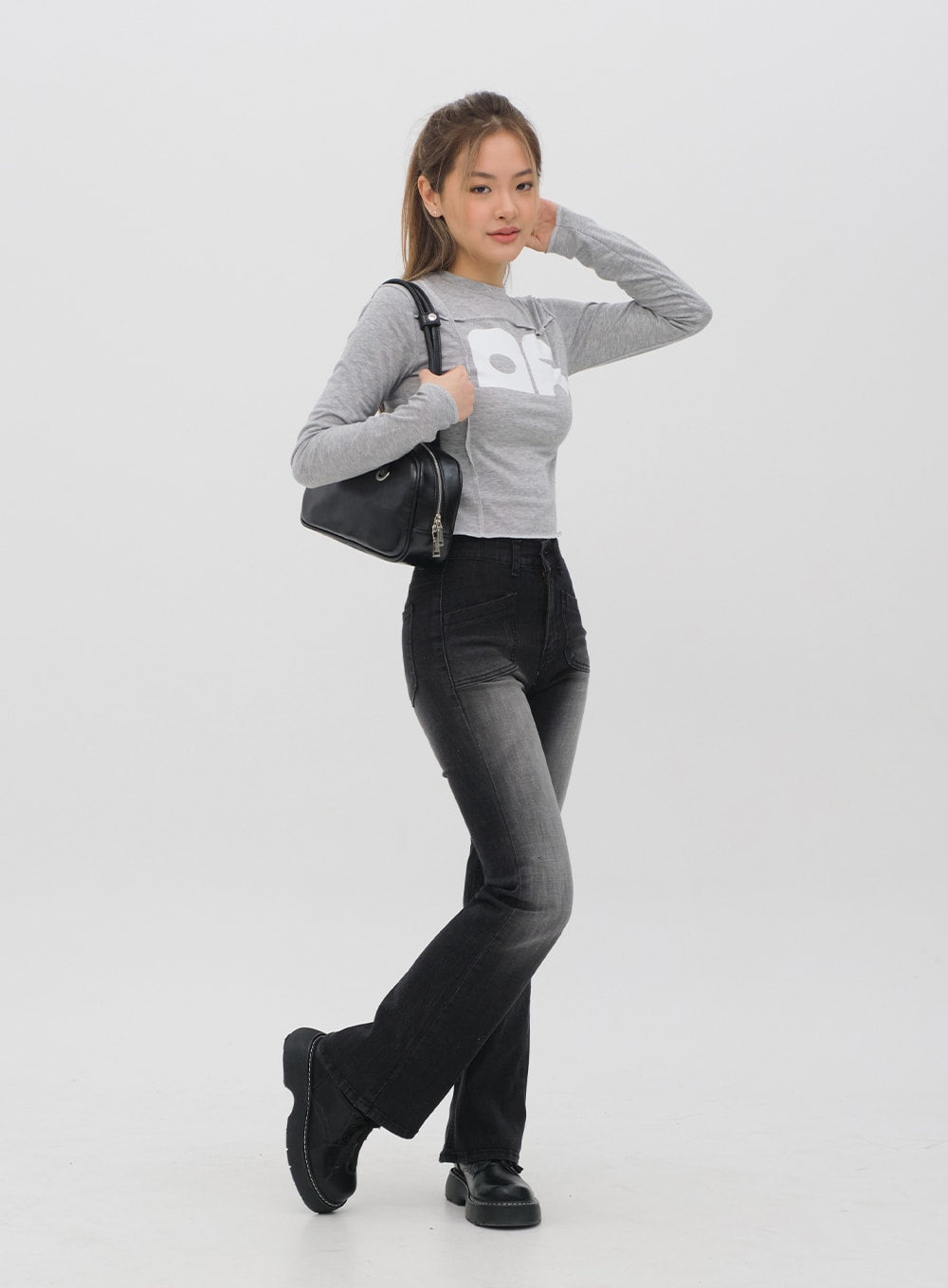 Bootcut Jeans M4 in black gradation wash, side-angled full-body shot on model, bootcut flare silhouette visible, high waist, paired with grey crop top and black handbag.