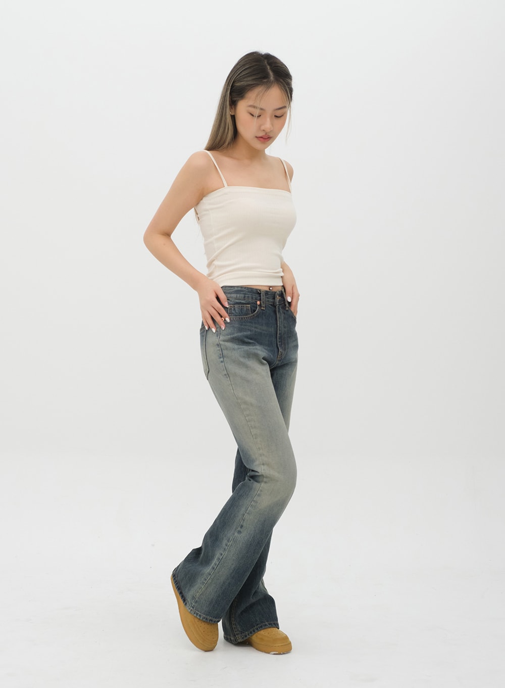 Boot Cut Jeans J20 in Dark Denim, three-quarter side view on model in cream cami, gradation washed bootcut denim showing flared silhouette and pocket placement.